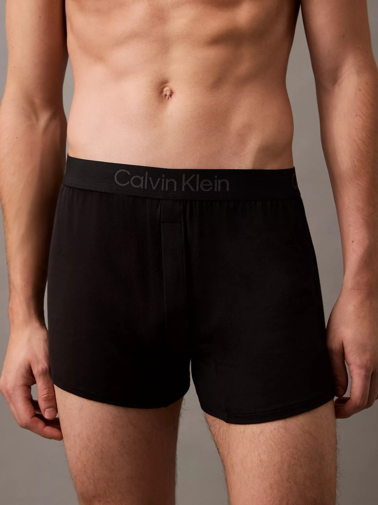 A close-up of a male model wearing black Calvin Klein boxer briefs, showing the waistband with the brand name in light gray text. Calvin Klein, Monza Outlet, Monza Fashion, Shein Outlet