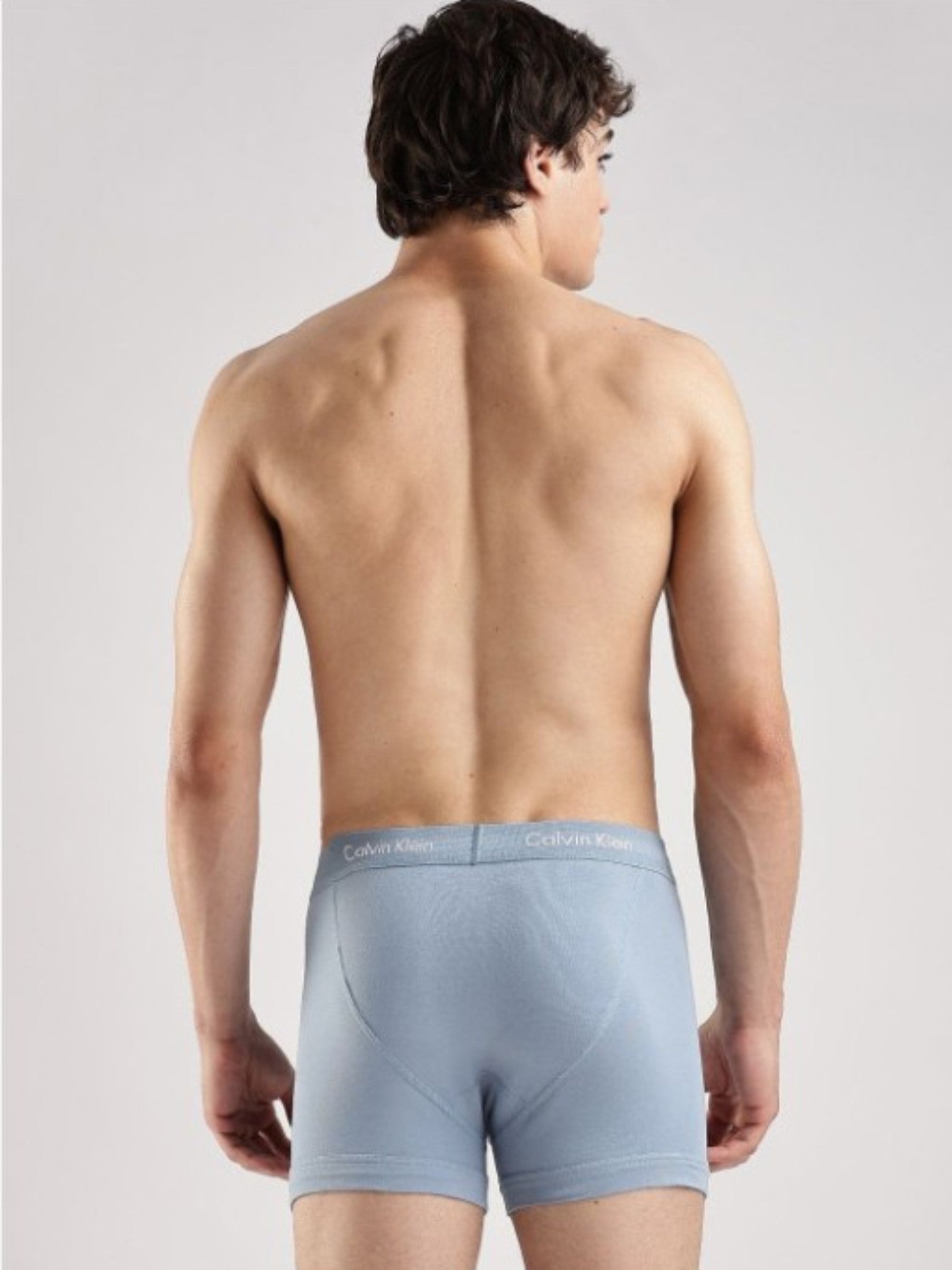A man shown from the back wearing light blue Calvin Klein boxer briefs against a light gray studio background. Calvin Klein, Monza Outlet, Monza Fashion, Shein Outlet