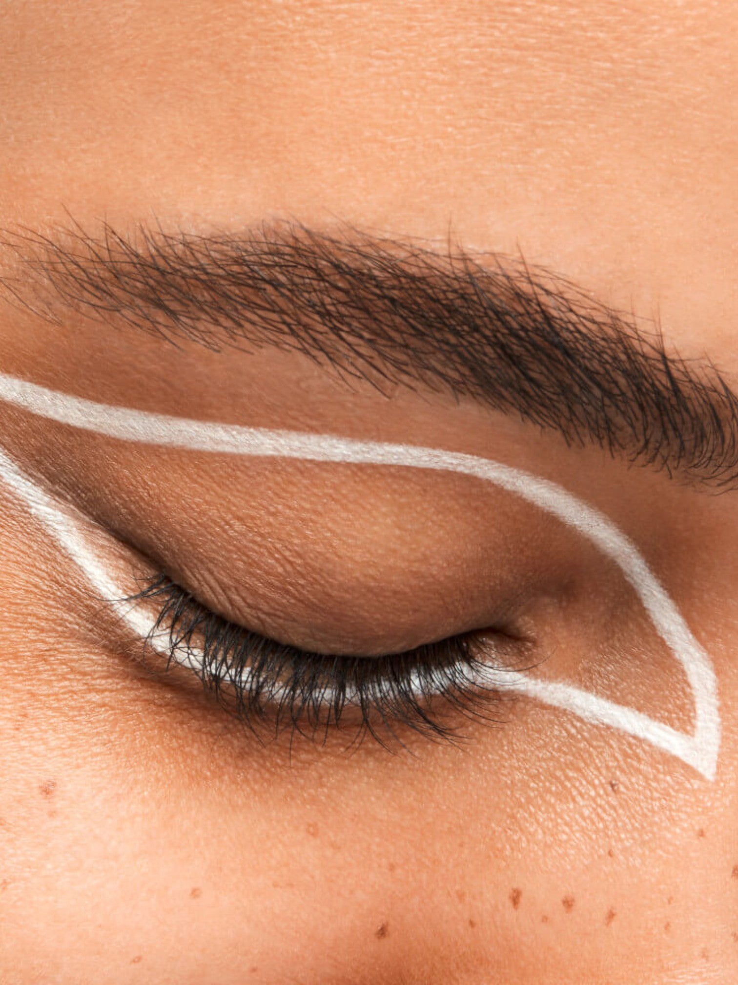 Close-up of a person's eye with white eyeliner on a neutral background. Shiseido, Monza Outlet, Monza Fashion, Shein Outlet