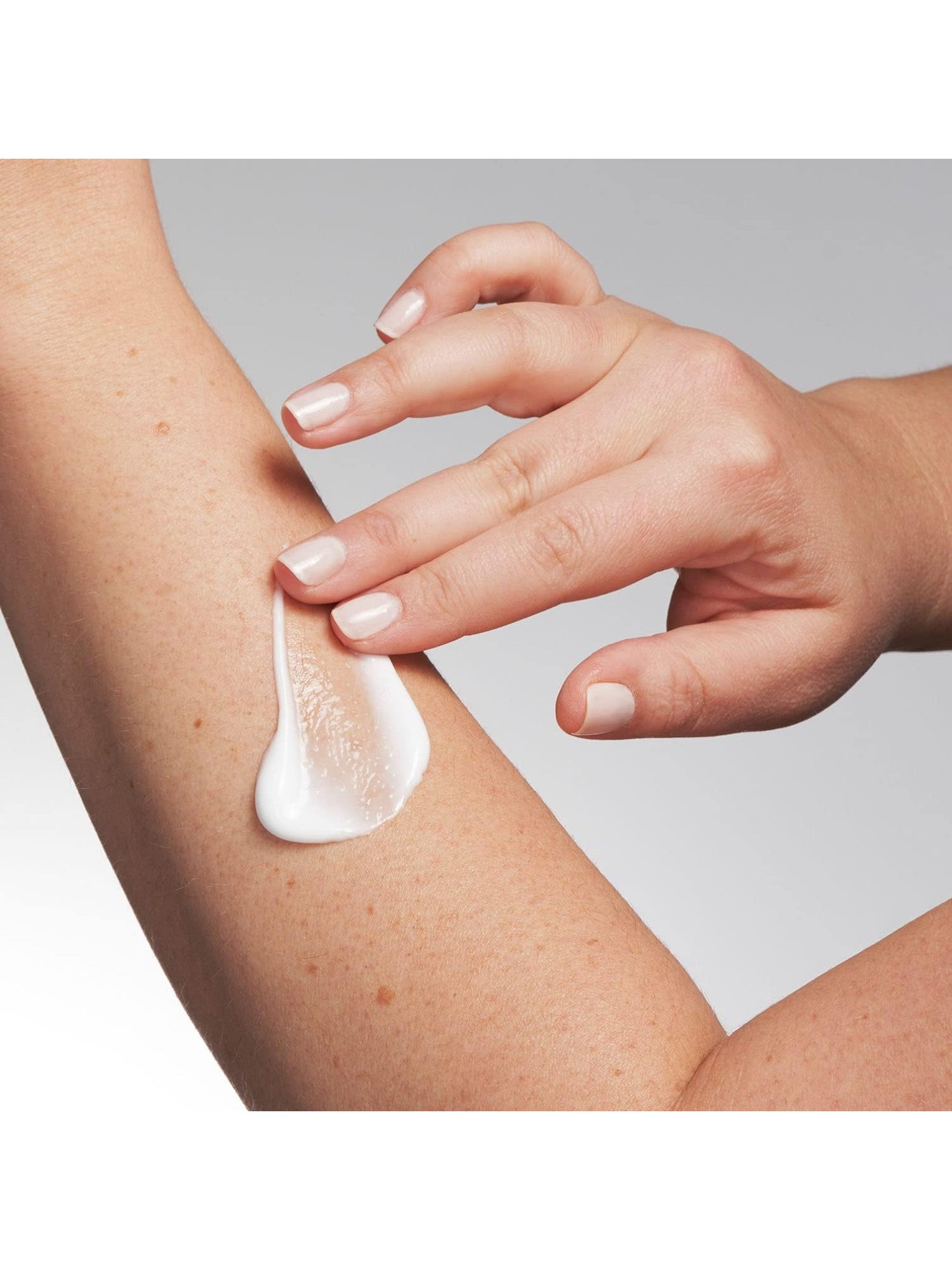 Hand applying cream to a person's arm on a gray background. Neostrata, Monza Outlet, Monza Fashion, Shein Outlet