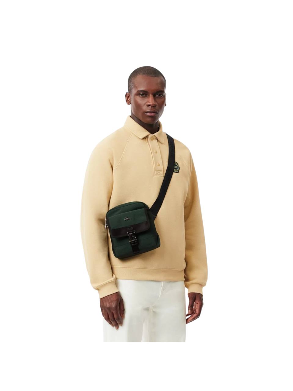 Man wearing a beige sweater with a green crossbody bag on a white background Lacoste Monza Outlet, Monza Fashion, Shein Outlet
