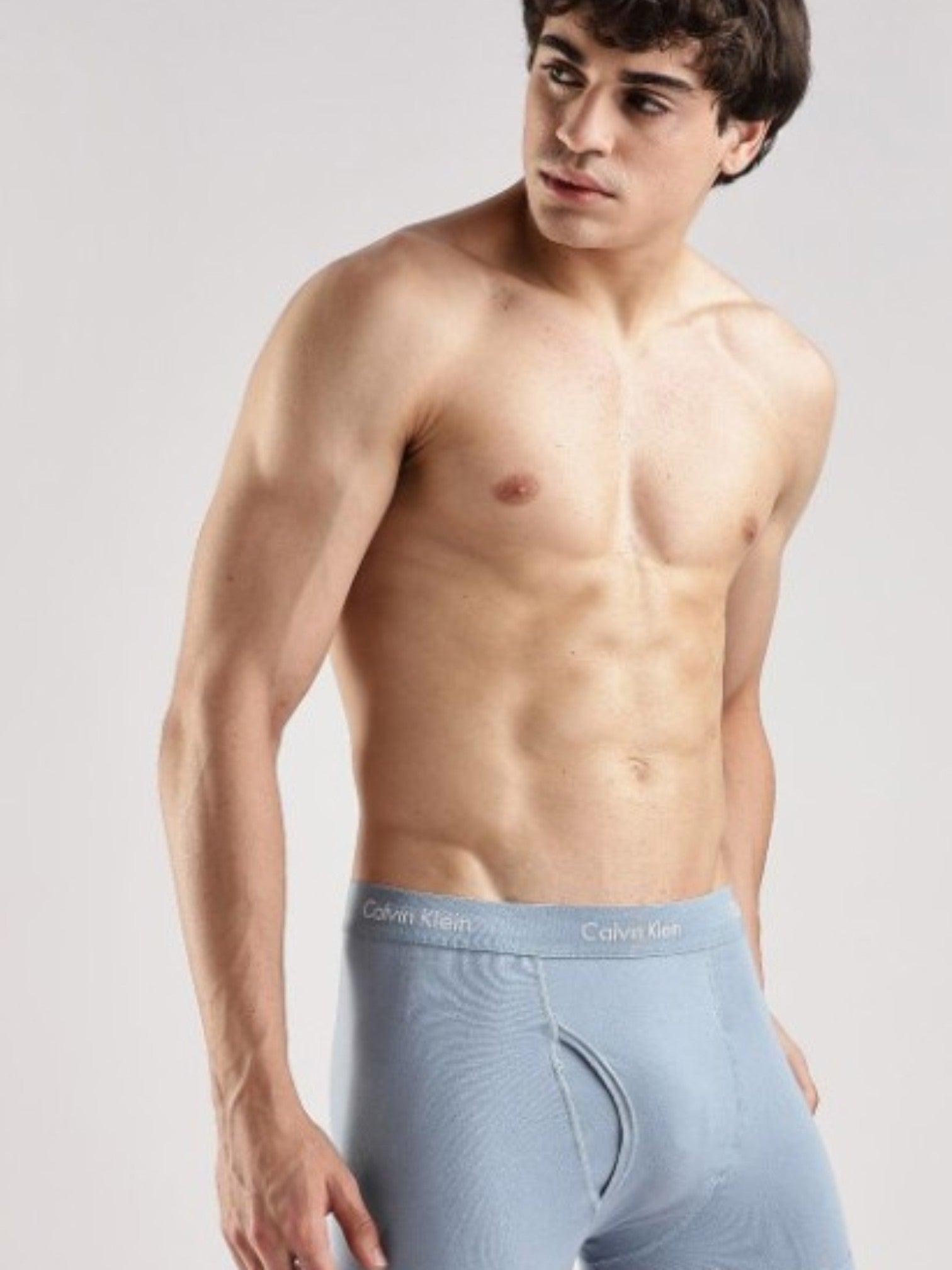 A shirtless male model wearing light blue Calvin Klein briefs, photographed against a plain light gray studio background. Calvin Klein, Monza Outlet, Monza Fashion, Shein Outlet
