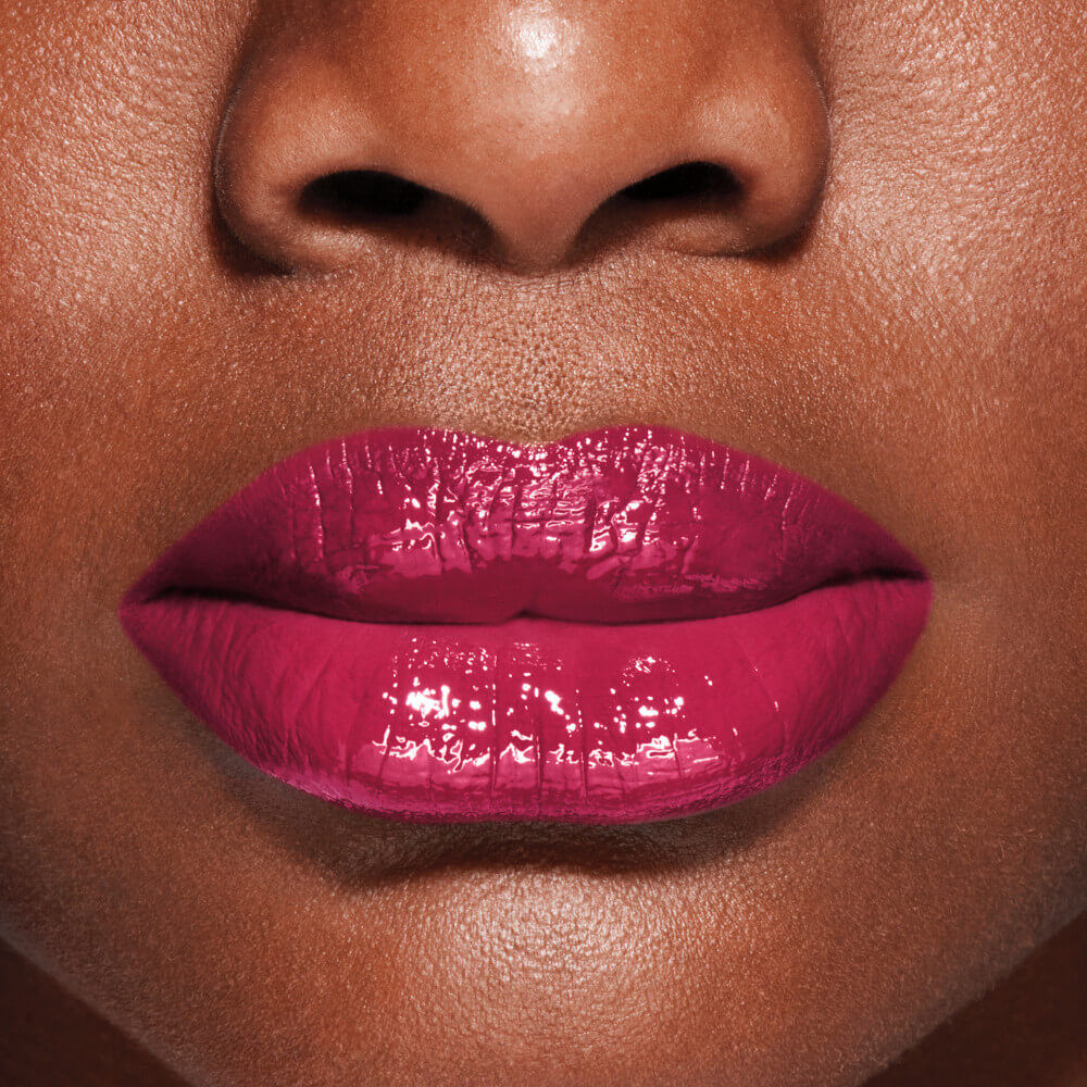Close-up of a person's lips wearing bright pink lipstick on a matching skin tone.