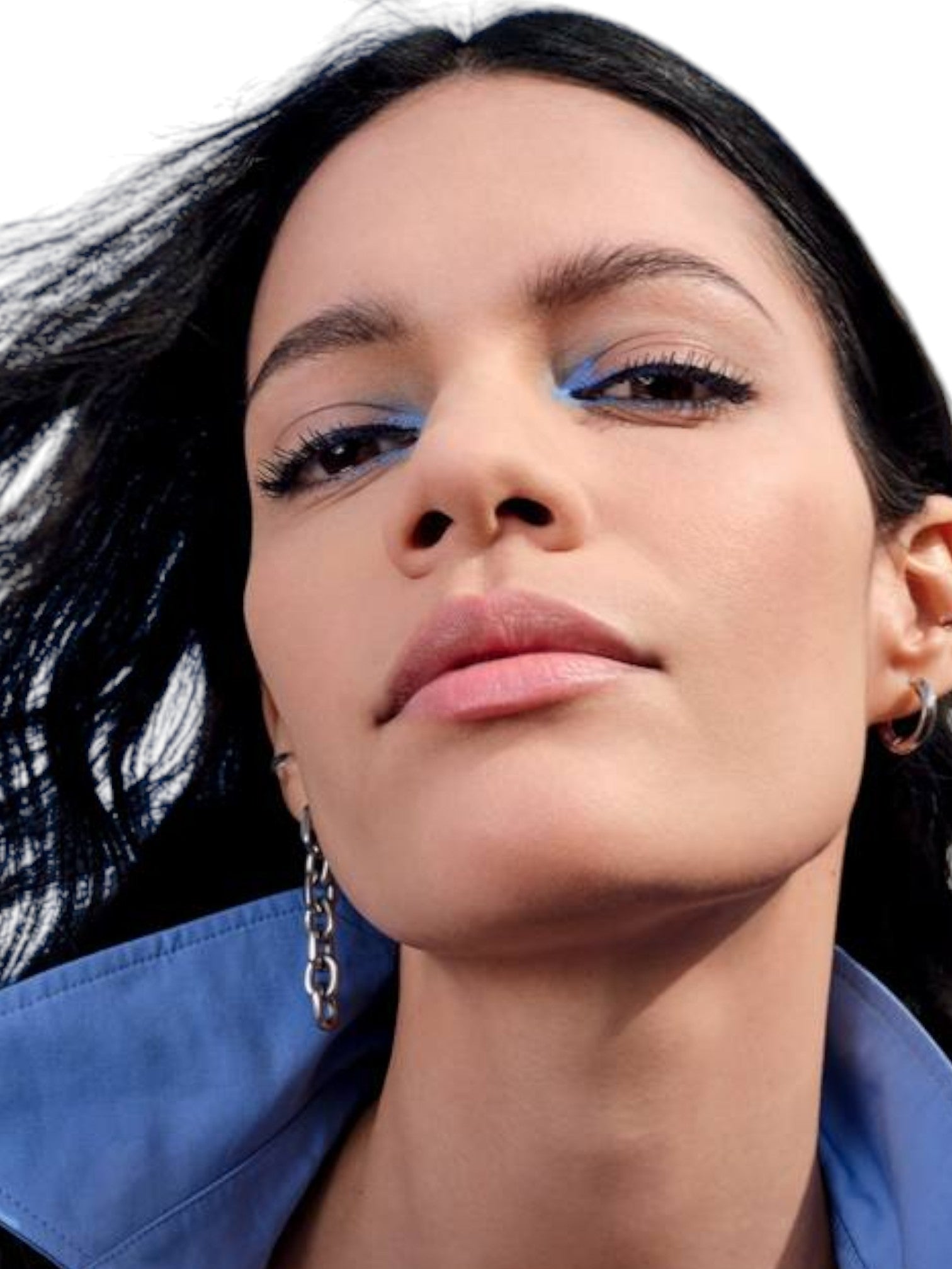 Close-up of a woman with dark hair and blue eyeshadow, wearing a blue shirt Maybelline Monza Outlet