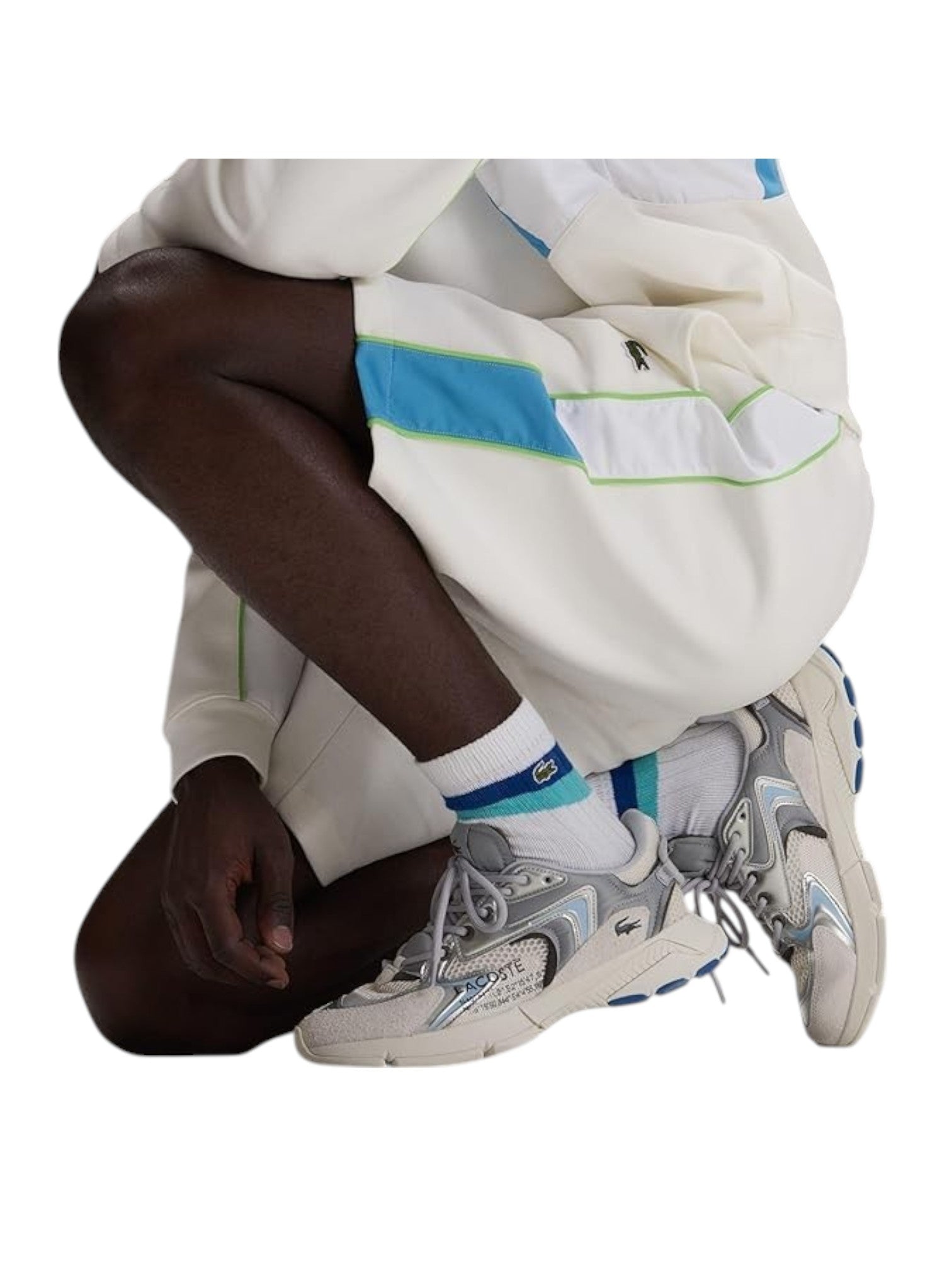 Person wearing a white outfit with blue and green accents, sitting on a white background Lacoste Monza Outlet