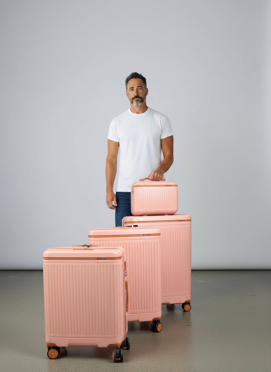 Man holding a pink suitcase with a set of matching suitcases on a gray background. Monza Italy, Monza Outlet, Monza Fashion, Shein Outlet