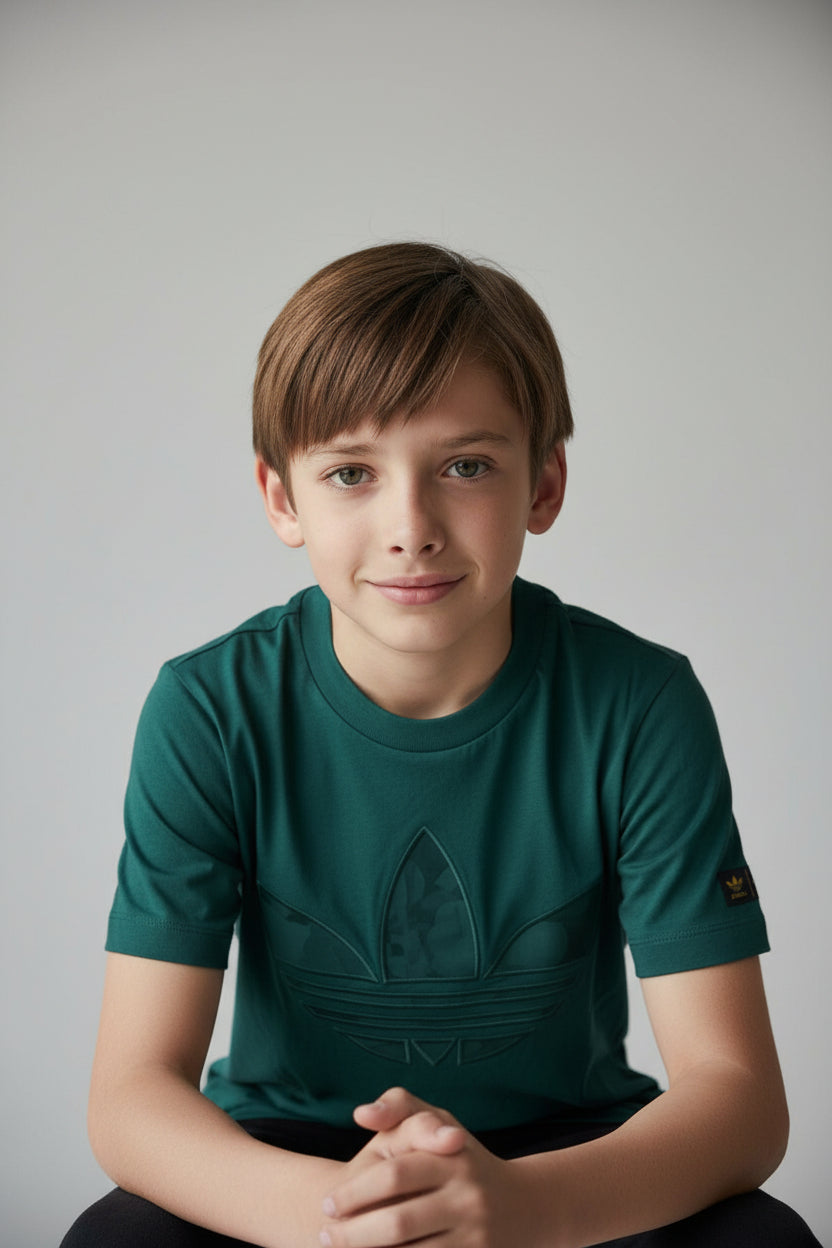 Young boy wearing a green t-shirt with a logo on a plain background. Adidas, Monza Outlet, Monza Fashion, Shein Outlet