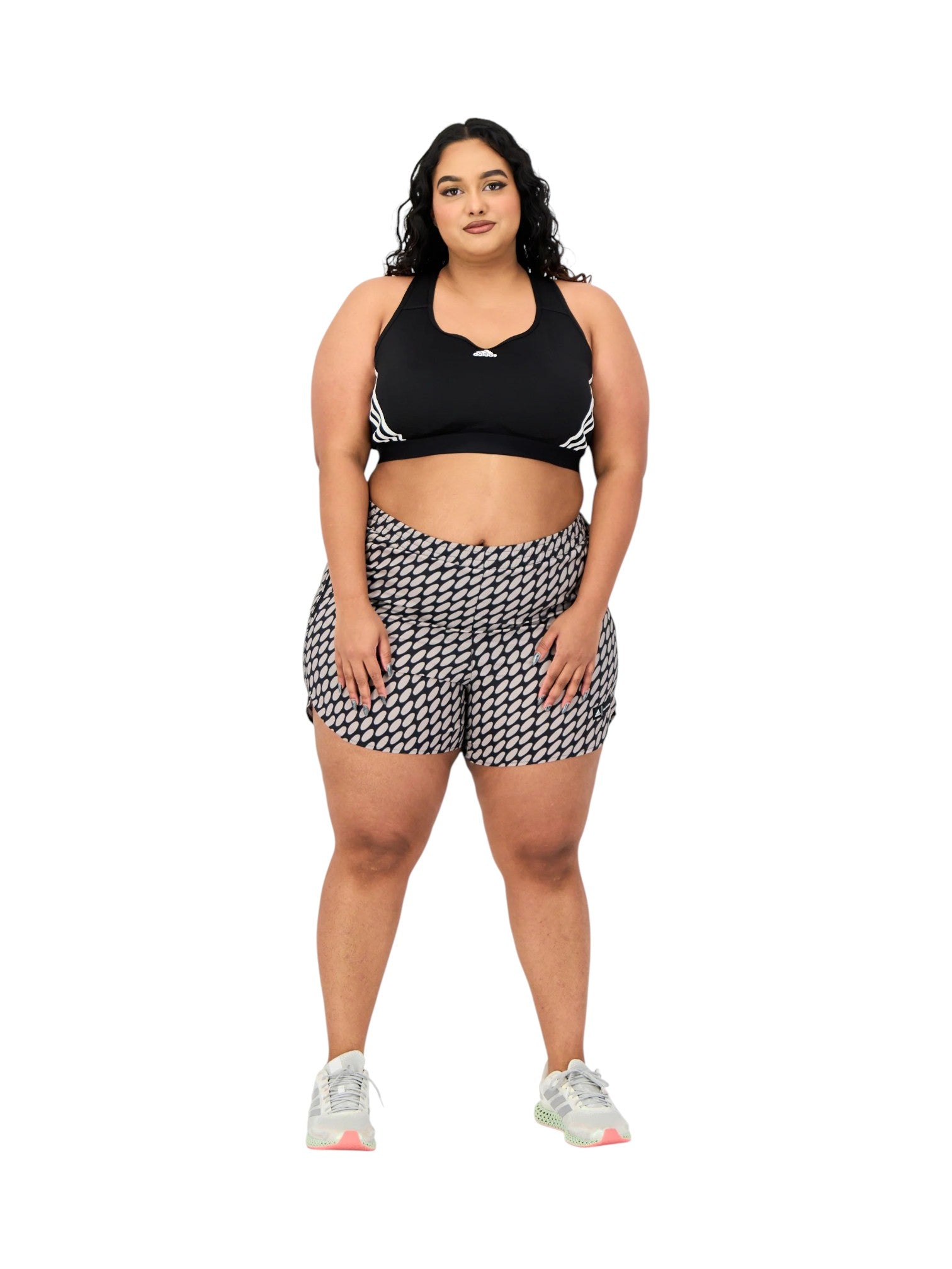 Woman wearing a black sports bra and houndstooth shorts on a white background. Adidas, Monza Outlet, Monza Fashion, Shein Outlet