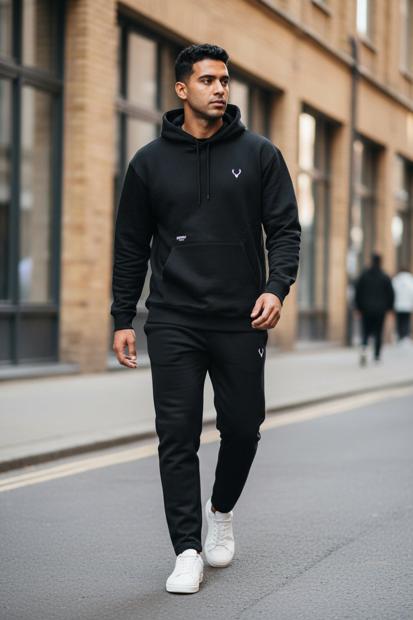 Man wearing a black hoodie and pants walking on a street. Antler, Monza Outlet, Monza Fashion, Shein Outlet