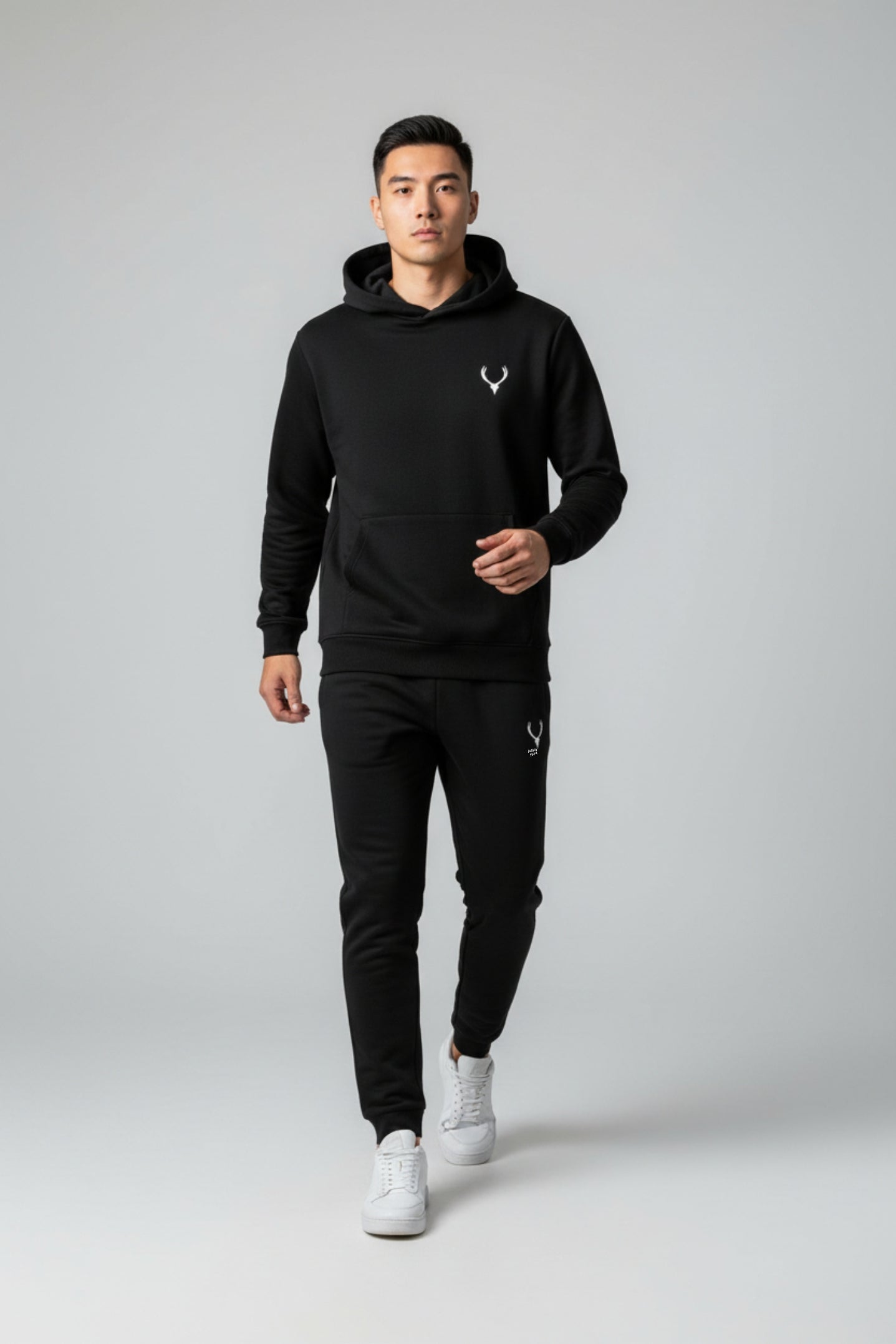 Man wearing a black hoodie and pants with a logo on a gray background. Antler, Monza Outlet, Monza Fashion, Shein Outlet