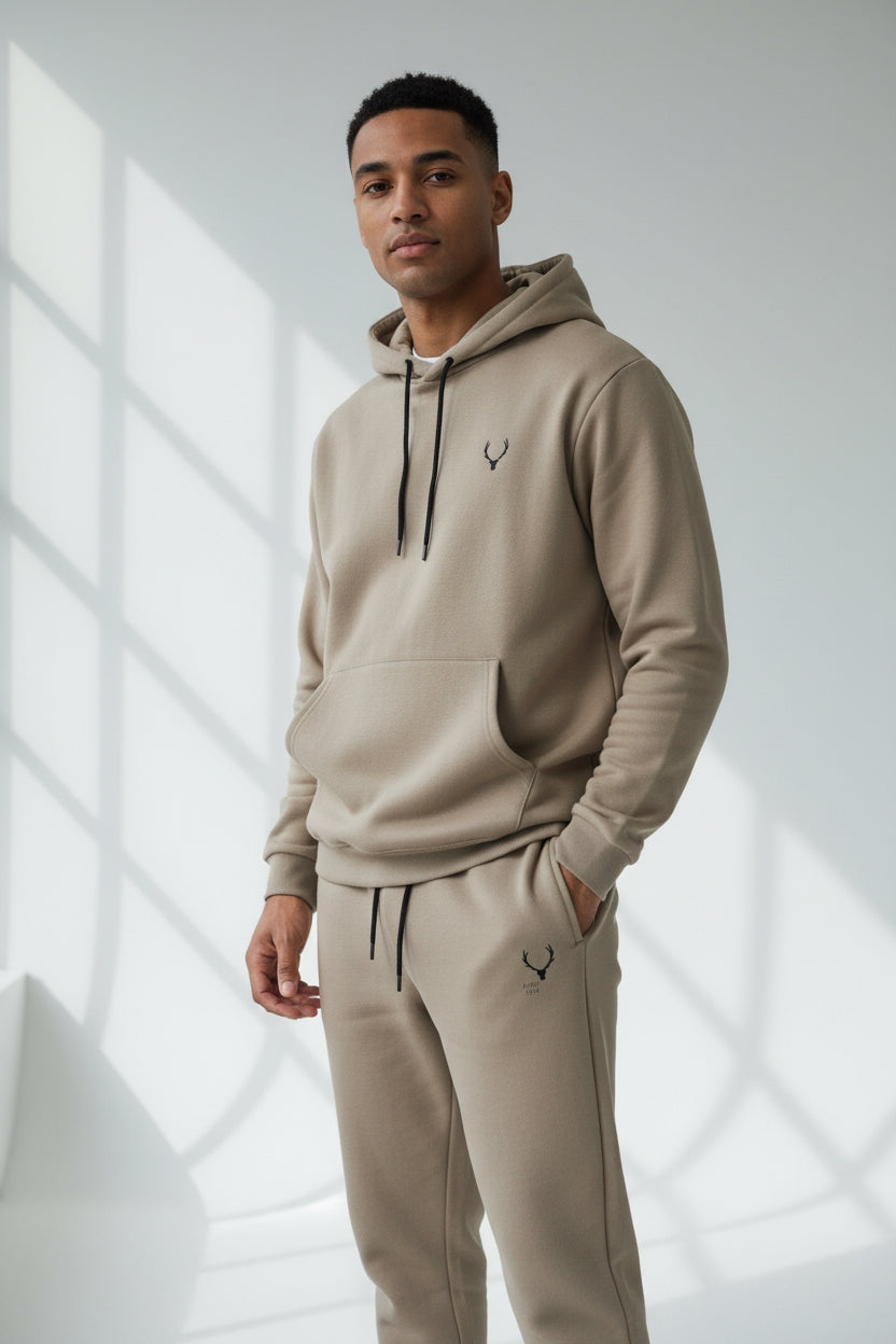 Man wearing a beige hoodie and pants with a logo, standing in a well-lit room. Antler, Monza Outlet, Monza Fashion, Shein Outlet