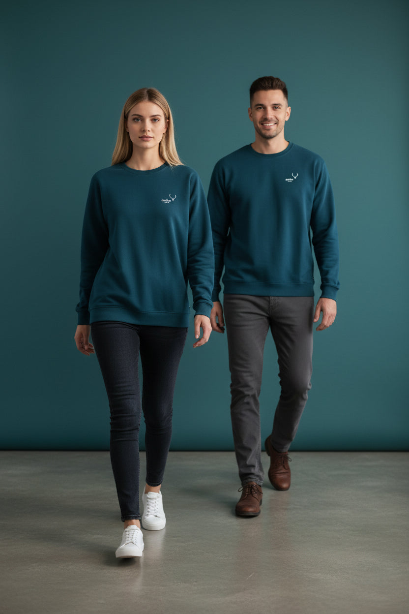 Two people wearing matching teal sweatshirts against a dark blue background. Antler, Monza Outlet, Monza Fashion, Shein Outlet
