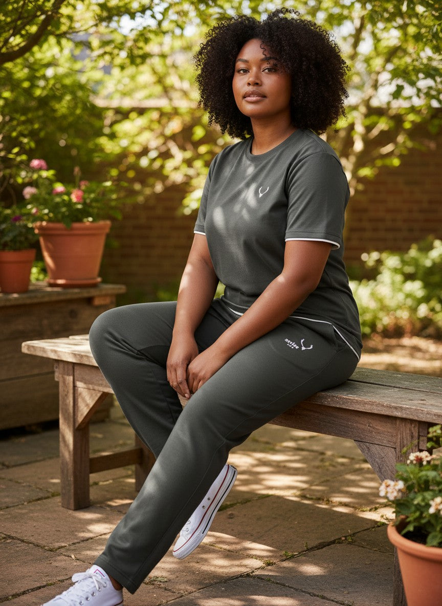 Woman sitting on a wooden bench outdoors wearing a gray outfit with a brand logo. Antler, Monza Outlet, Monza Fashion, Shein Outlet 