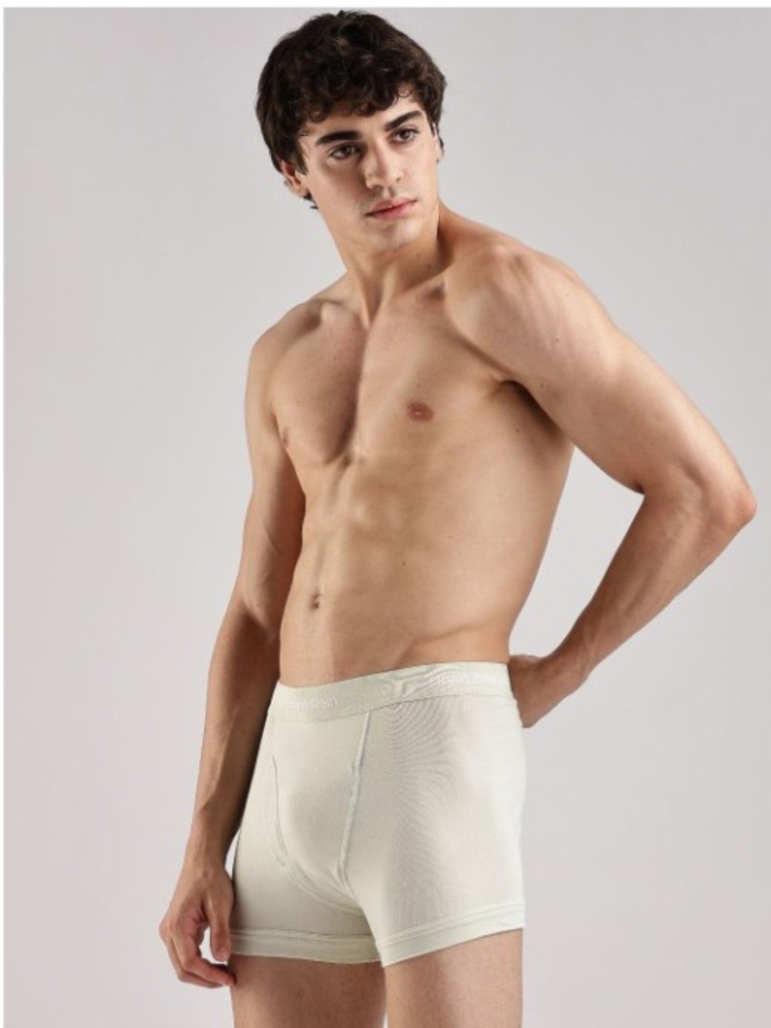 A shirtless male model wearing light cream off white boxer briefs, photographed against a plain light gray studio background. Calvin Klein, Monza Outlet, Monza Fashion, Shein Outlet