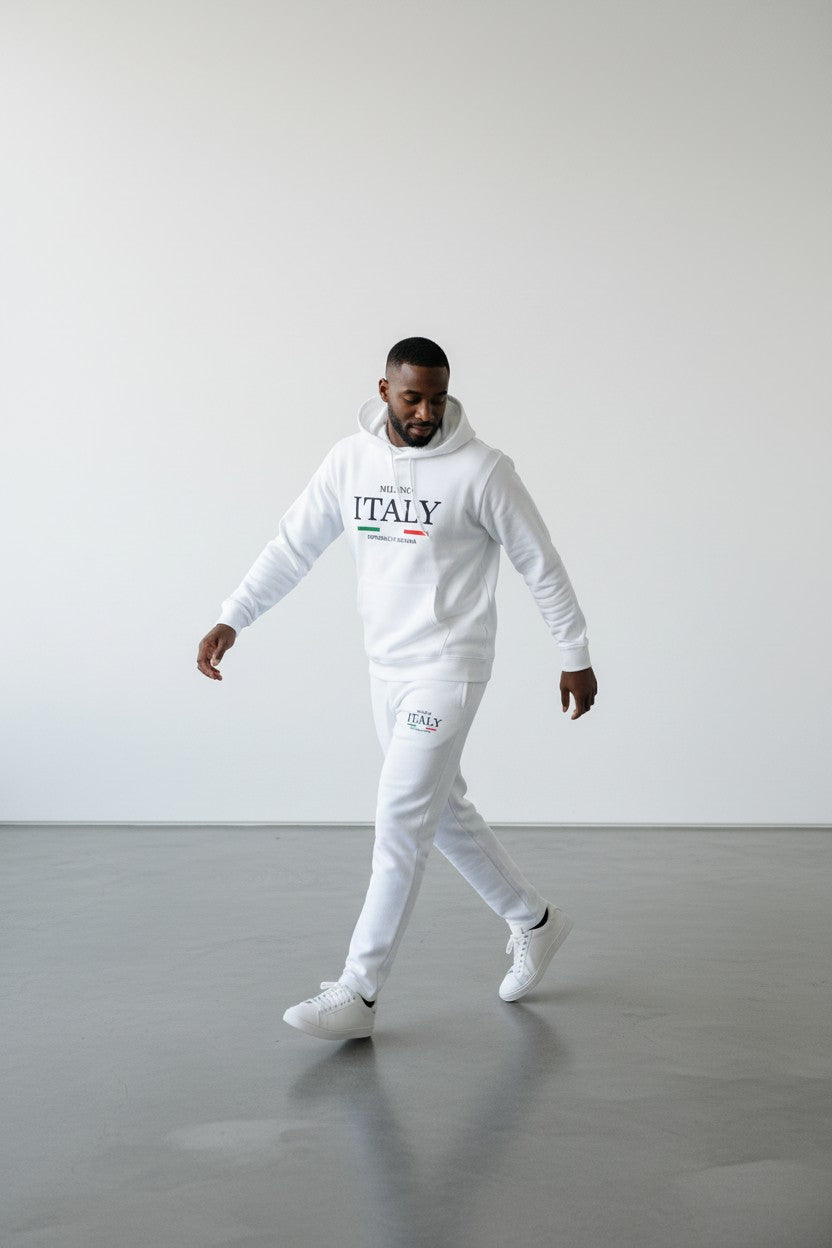 Person wearing a white hoodie with ITALY text and white pants on a gray floor. Antler, Monza Outlet, Monza Fashion, Shein Outlet