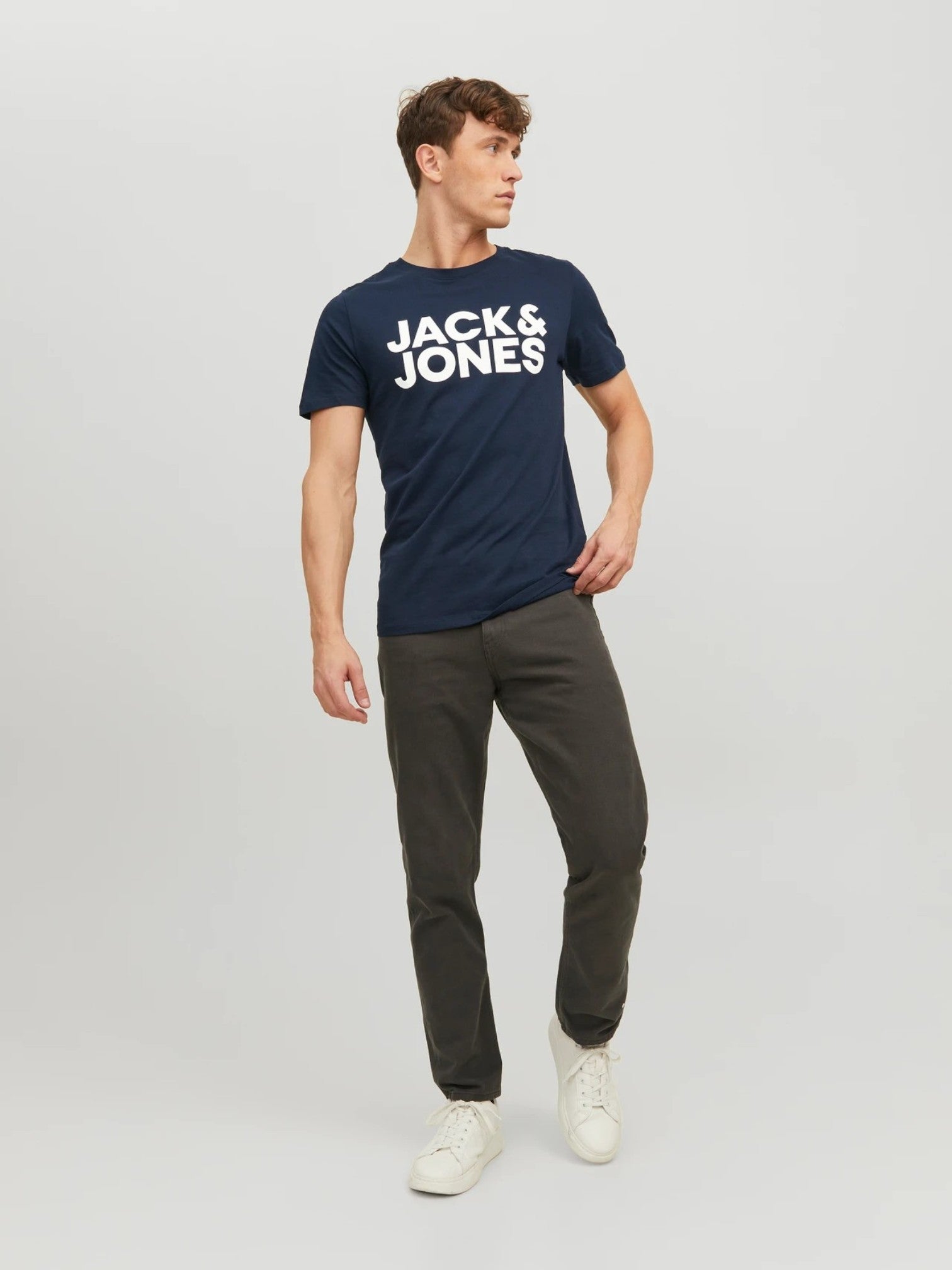 Man wearing a navy 'Jack & Jones' t-shirt with gray pants on a light gray background. Jack & Jones, Monza Outlet, Monza Fashion, Shein Outlet 