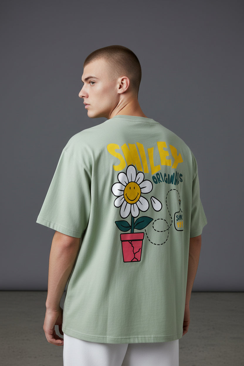 Person wearing a light green t-shirt with a flower graphic and text on the back against a gray background. Monza Outlet, Monza Fashion, Shein Outlet