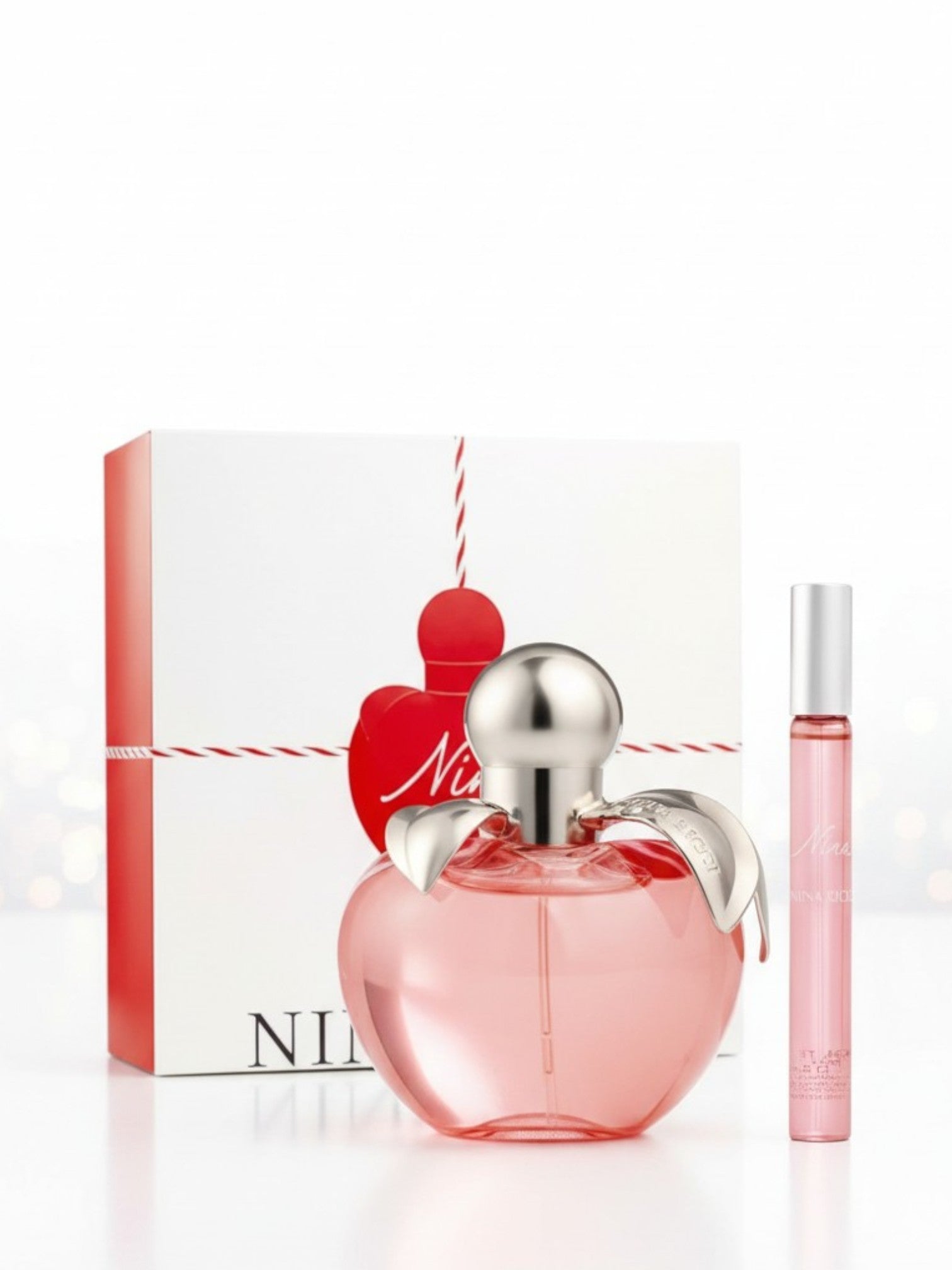 Perfume bottle with silver cap and red heart design, next to its packaging on a white background. Nina Ricci, Monza Outlet, Monza Fashion, Shein Outlet