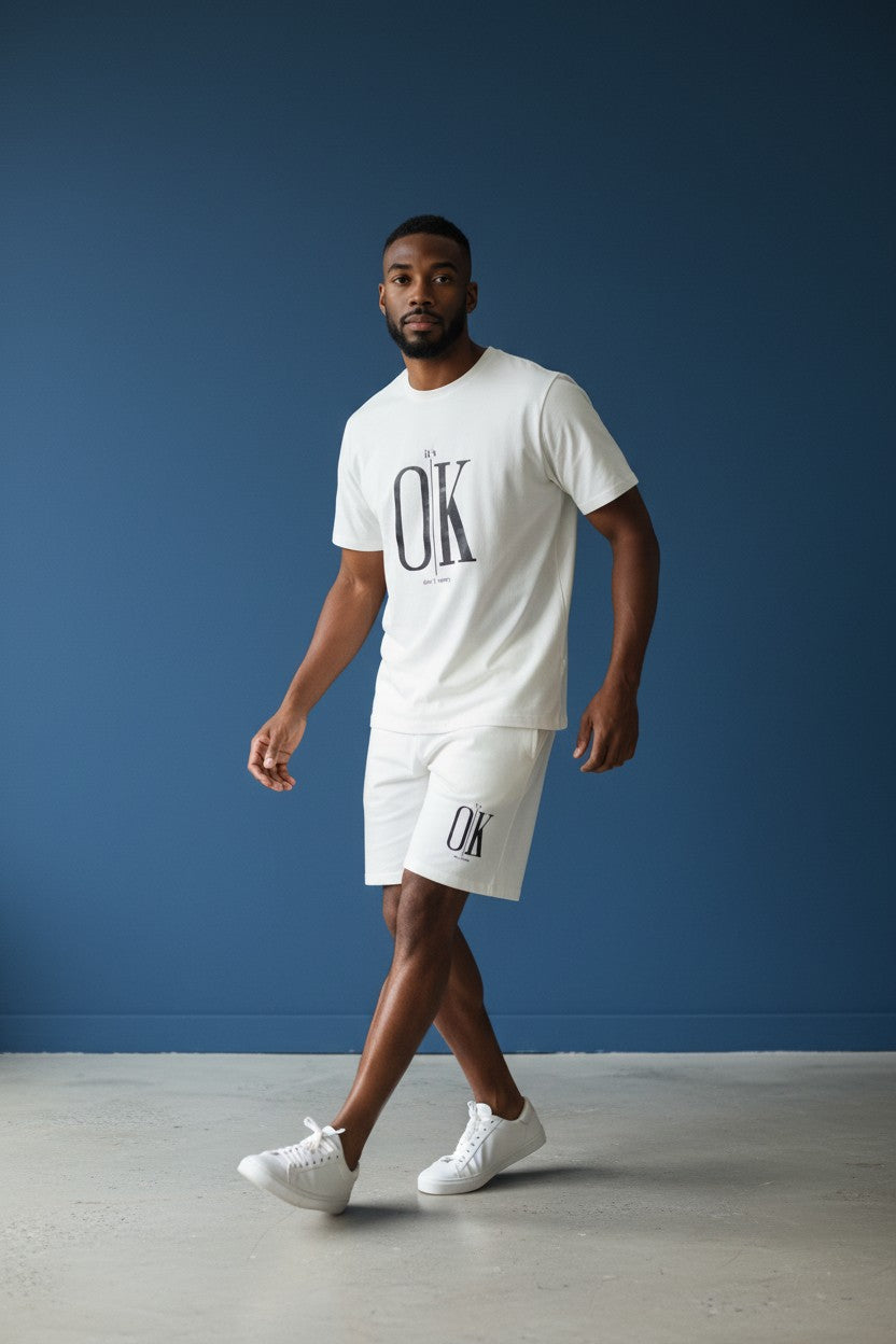 Man wearing a white t-shirt and shorts with OK logo against a blue background. Antler, Monza Outlet, Monza Fashion, Shein Outlet