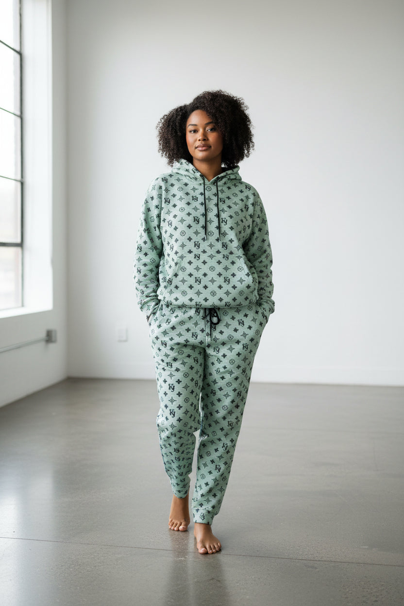 Person wearing a green patterned hoodie and pants in a minimalistic room. Antler, Monza Outlet, Monza Fashion, Shein Outlet