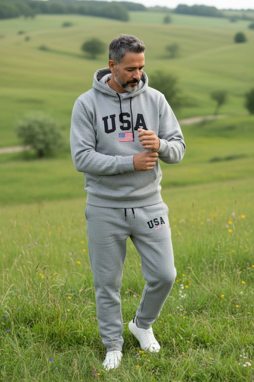Man wearing a gray USA tracksuit standing in a green field. Antler, Monza Outlet, Monza Fashion, Shein Outlet