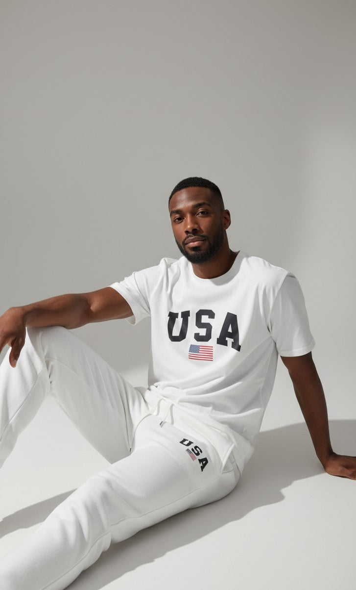 Man wearing a white USA t-shirt and pants on a light gray background. Antler, Monza Outlet, Monza Fashion, Shein Outlet