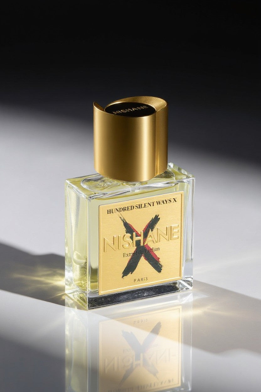 Perfume bottle with gold cap and label on a reflective surface. Nishane, Monza Outlet, Monza Fashion, Shein Outlet