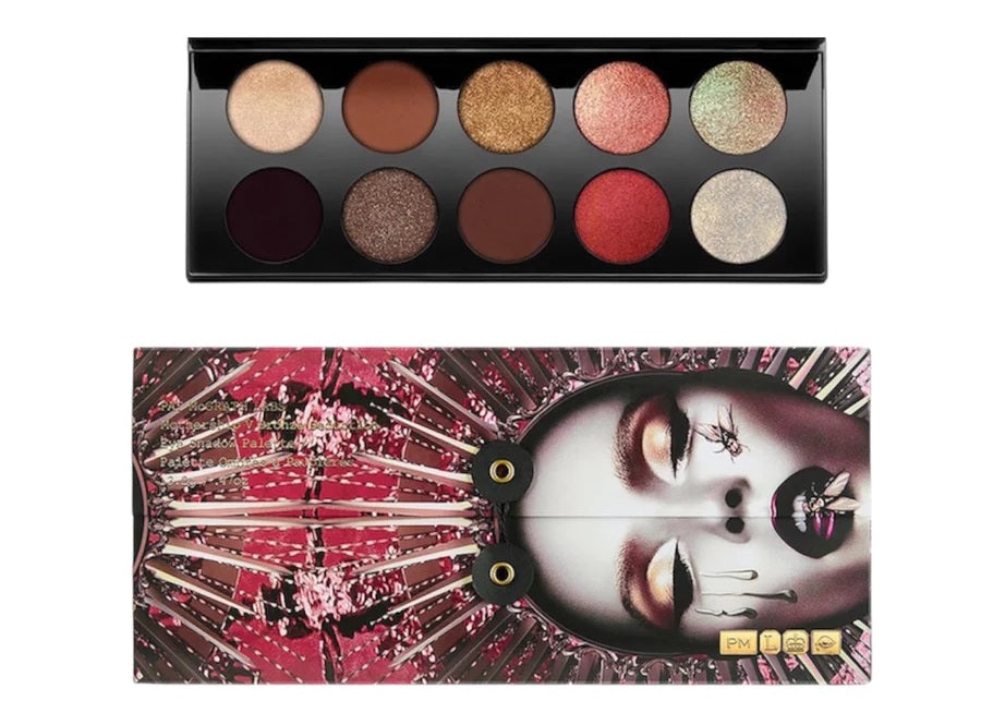 A makeup palette shown open above its illustrated case on a white background. The palette contains ten eyeshadow pans in neutral, metallic, and red tones, and the case features a stylized face illustration with pink, black, white, and metallic details. Monza Outlet, Monza Fashion, Shein Outlet