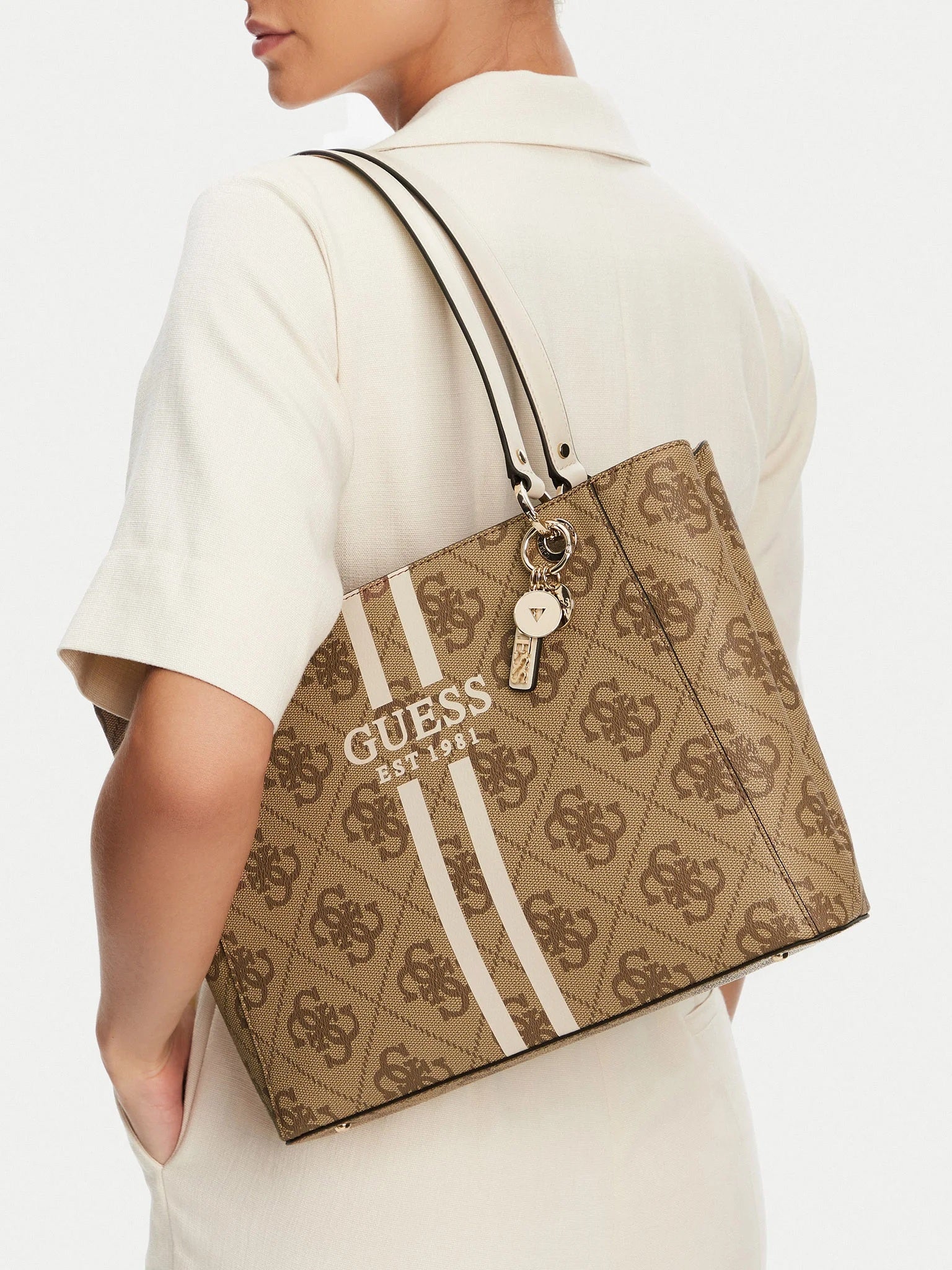 Person holding a brown Guess handbag with logo design. Guess, Monza Outlet, Monza Fashion, Shein Outlet