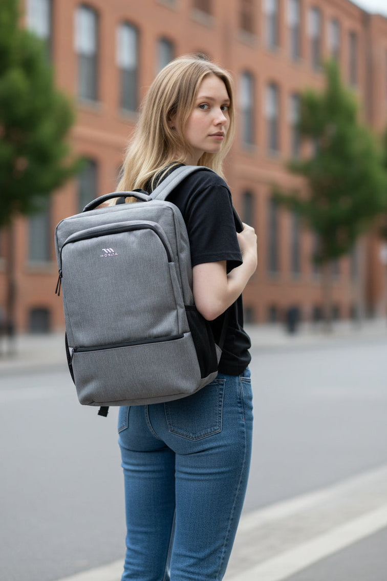 Woman wearing a gray backpack on a city street with a brick building in the background. Monza Italy, Monza Outlet, Monza Fashion, Shein Outlet