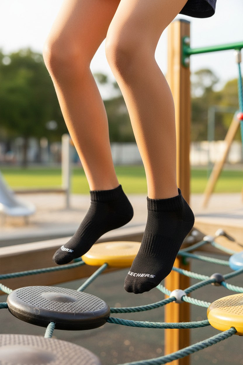 Person wearing black socks with visible branding on a playground. Skechers, Monza Outlet, Monza Fashion, Shein Outlet