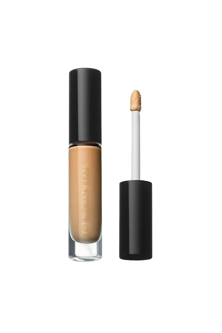 A bottle of Pat McGrath Labs Skin Fetish: Sublime Perfection Concealer with the cap off, showing the product in a medium shade with a dropper applicator. Monza Outlet