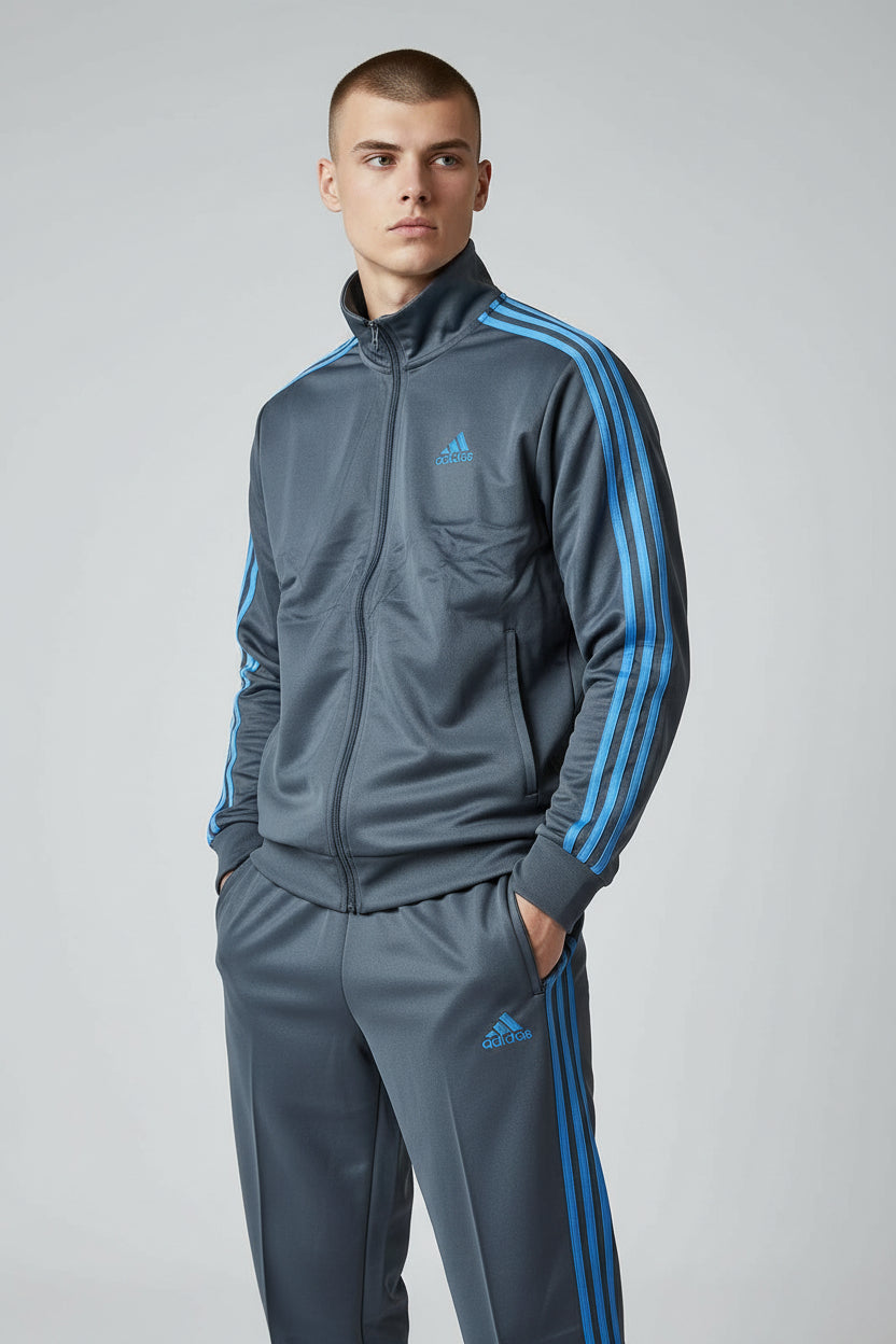 Man wearing a gray Adidas tracksuit with blue stripes on a light gray background. Adidas, Monza Outlet, Monza Fashion, Shein Outlet