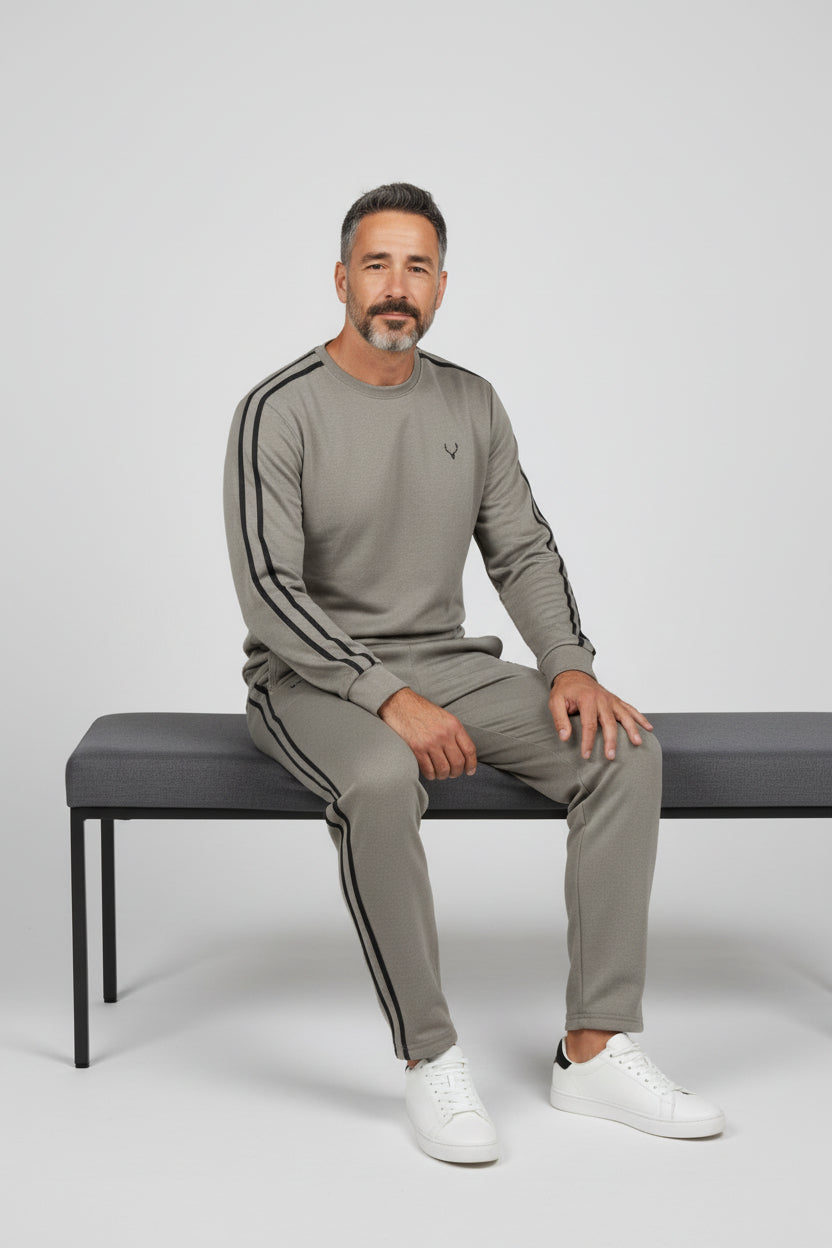 Man sitting on a bench wearing a gray tracksuit with white stripes. Antler, Monza Outlet, Monza Fashion, Shein Outlet