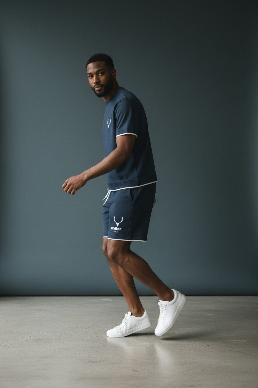 Man wearing a navy sports outfit with white accents against a gray background. Antler, Monza Outlet, Monza Fashion, Shein Outlet