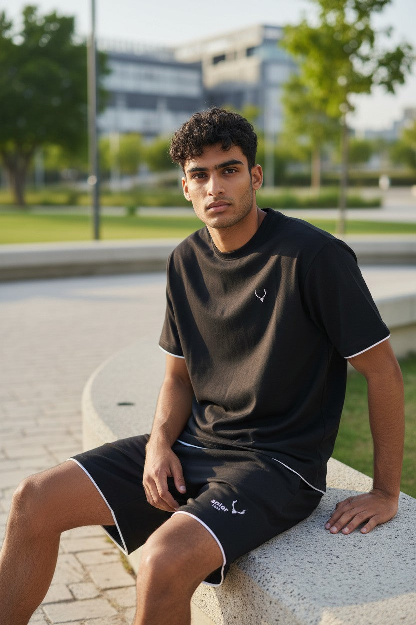 Man sitting outdoors wearing a black t-shirt and shorts. Antler, Monza Outlet, Monza Fashion, Shein Outlet