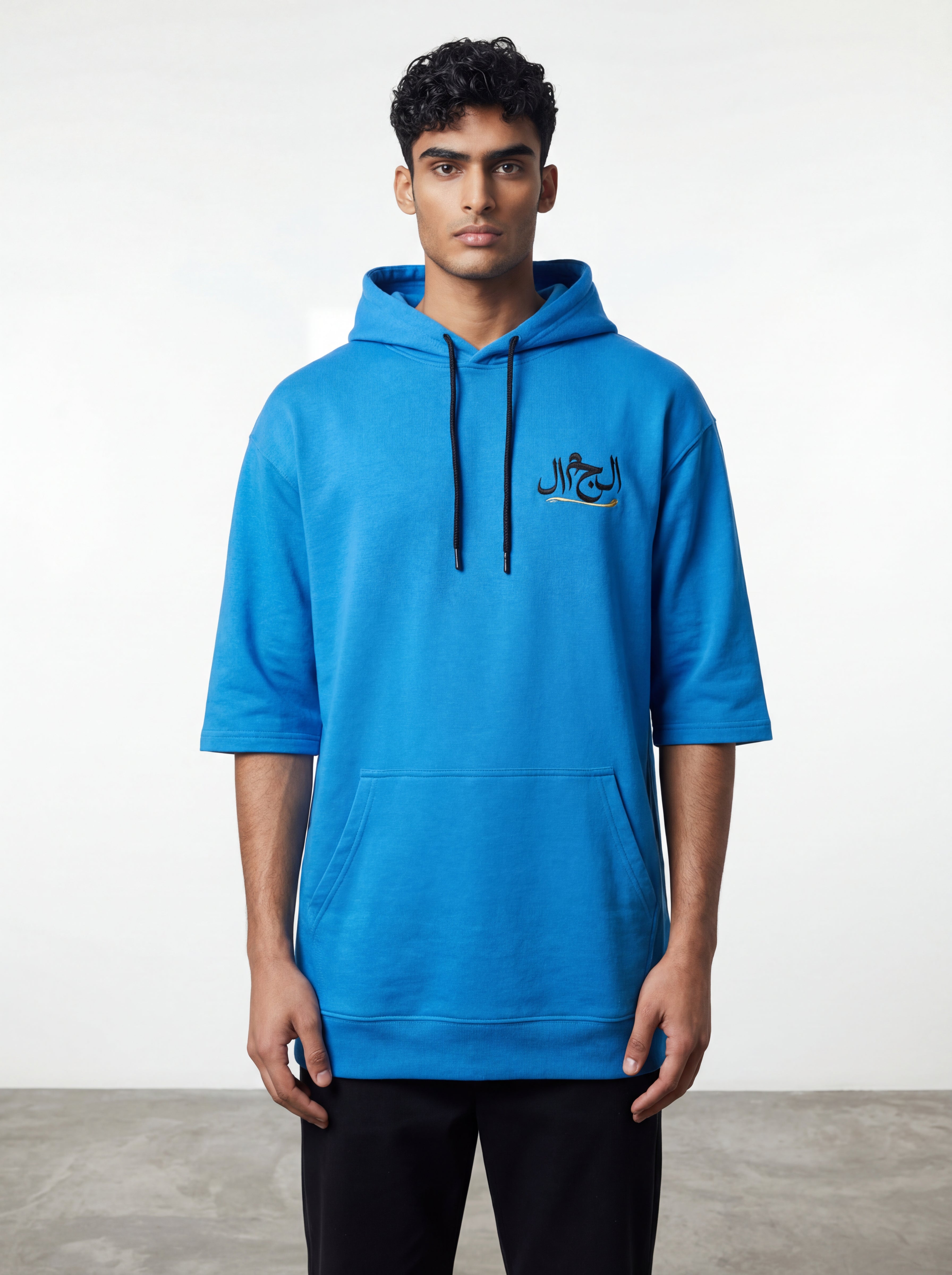 Man wearing a blue hoodie with Arabic text on a white background. 
