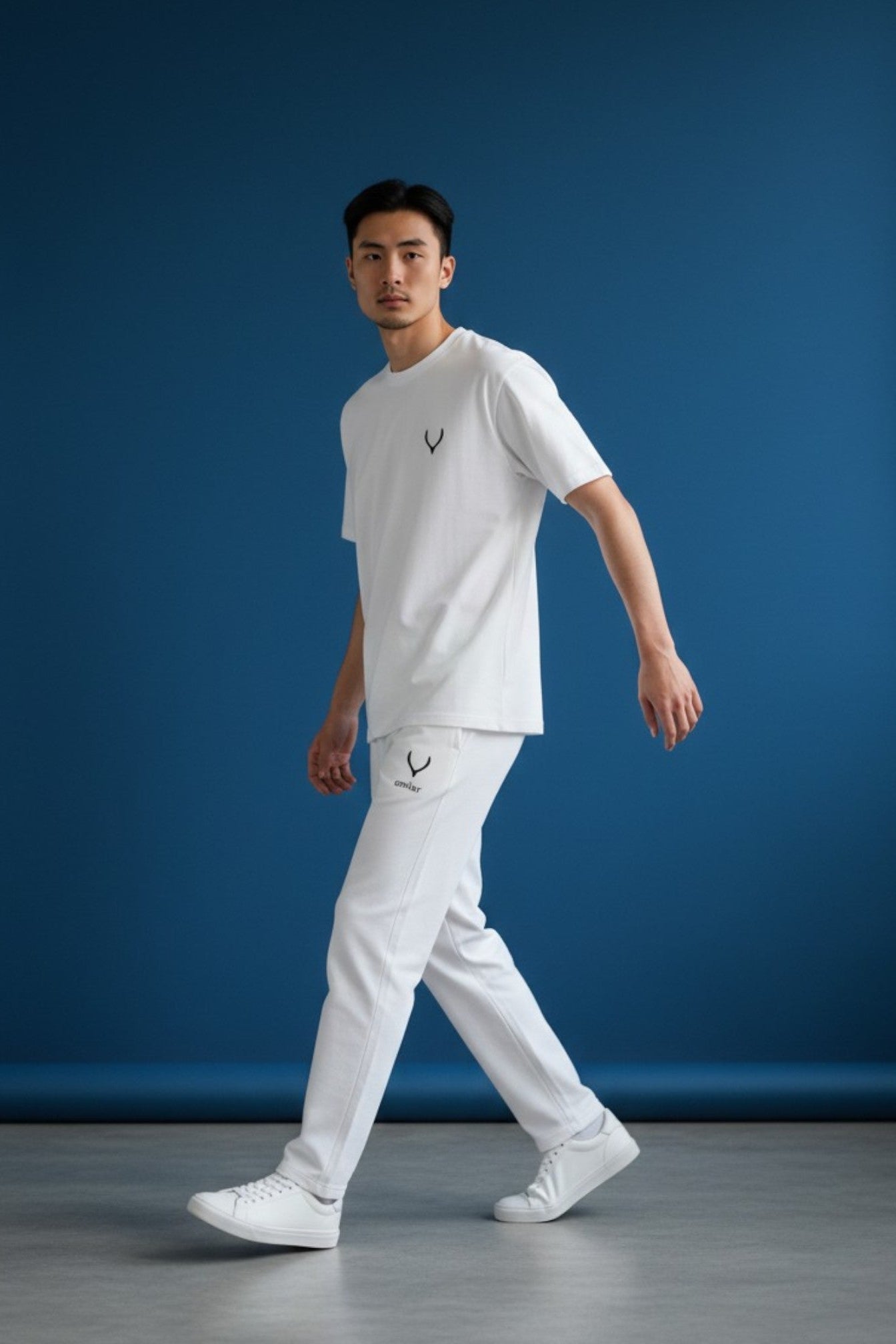 Man wearing a white t-shirt and pants with a logo against a blue background. Antler, Monza Outlet, Monza Fashion, Shein Outlet
