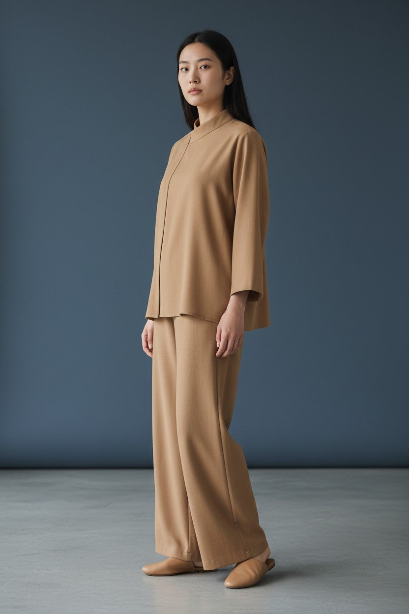 Woman wearing a beige suit standing against a blue background. Antler, Monza Outlet, Monza Fashion, Shein Outlet