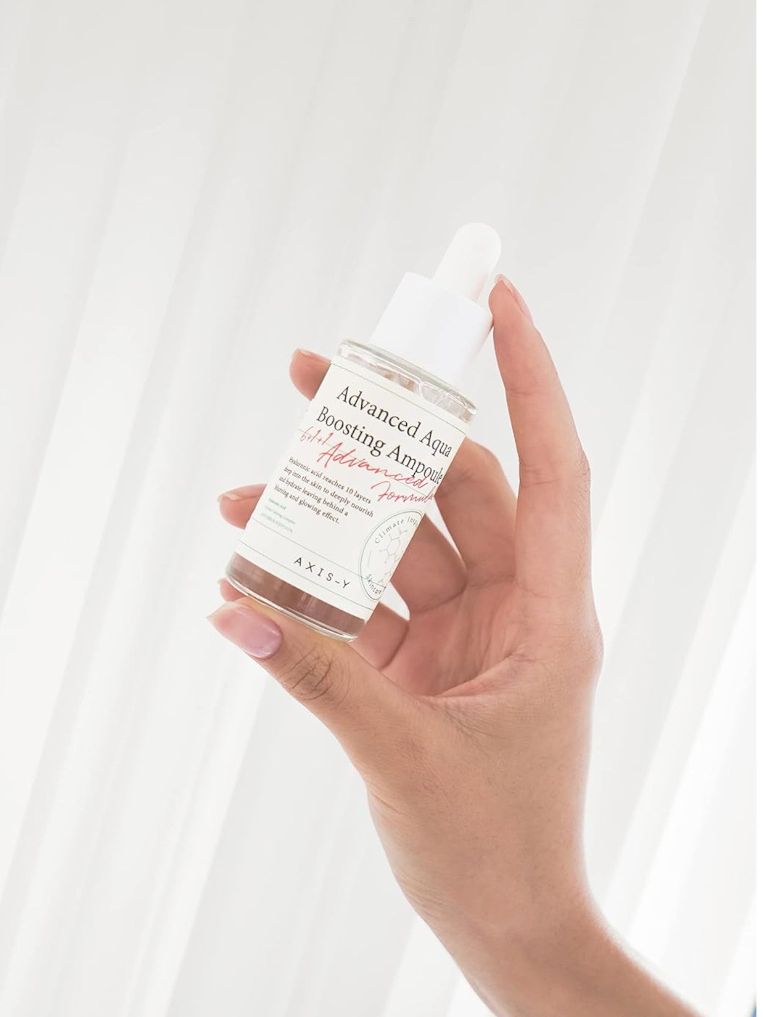 Hand holding a skincare product labeled 'Advanced Age Boosting Ampoule' against a white background. Axis-y, Monza Outlet, Monza Fashion, Shein Outlet