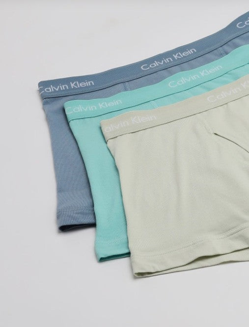 Three pairs of Calvin Klein mens boxer briefs in dusty blue, mint green, and light beige, arranged in a diagonal stack on a white background. Calvin Klein, Monza Outlet, Monza Fashion, Shein Outlet