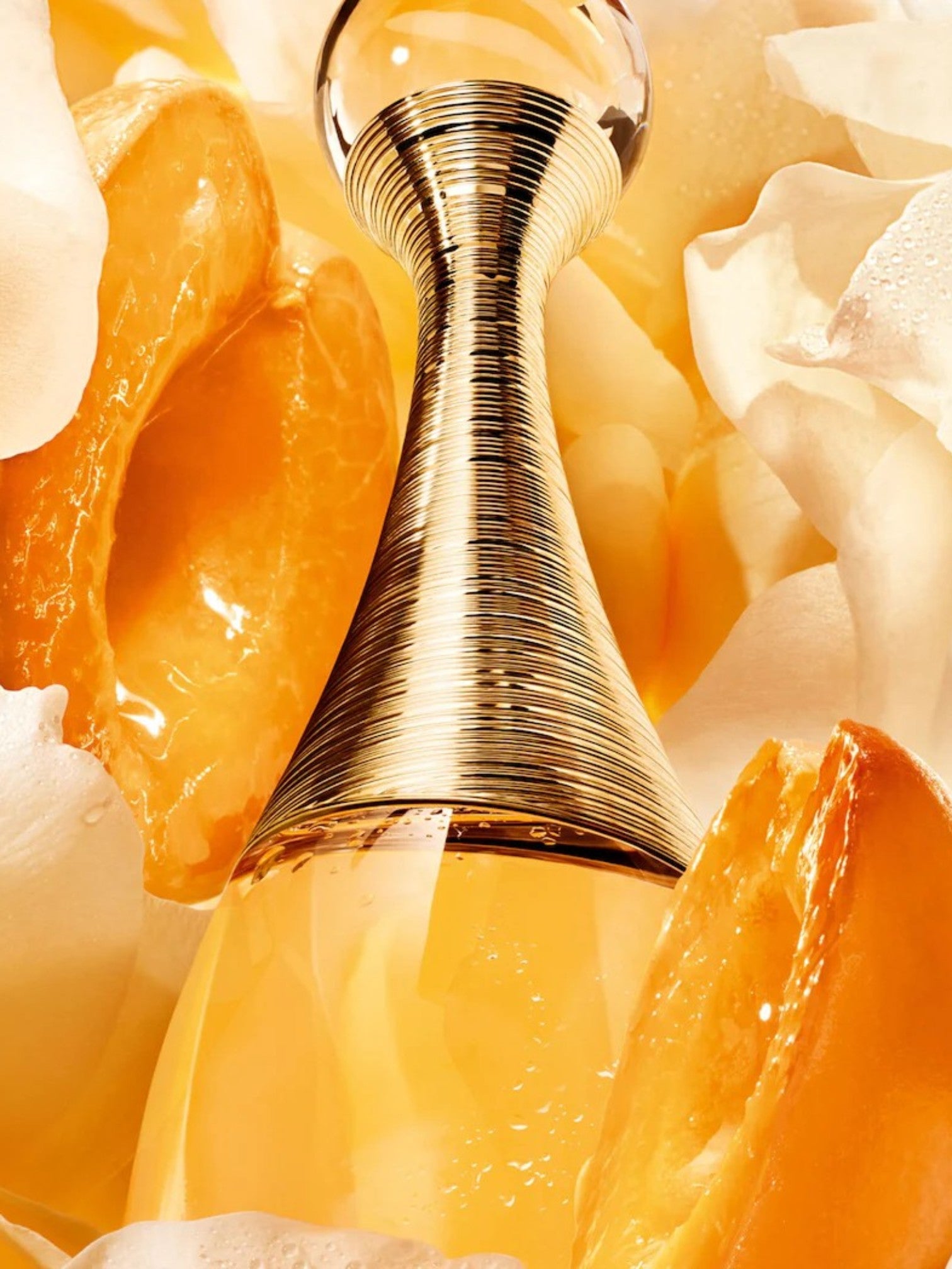 Gold perfume bottle with orange slices and flowers on a yellow background. Dior, Monza Outlet, Monza Fashion, Shein Outlet