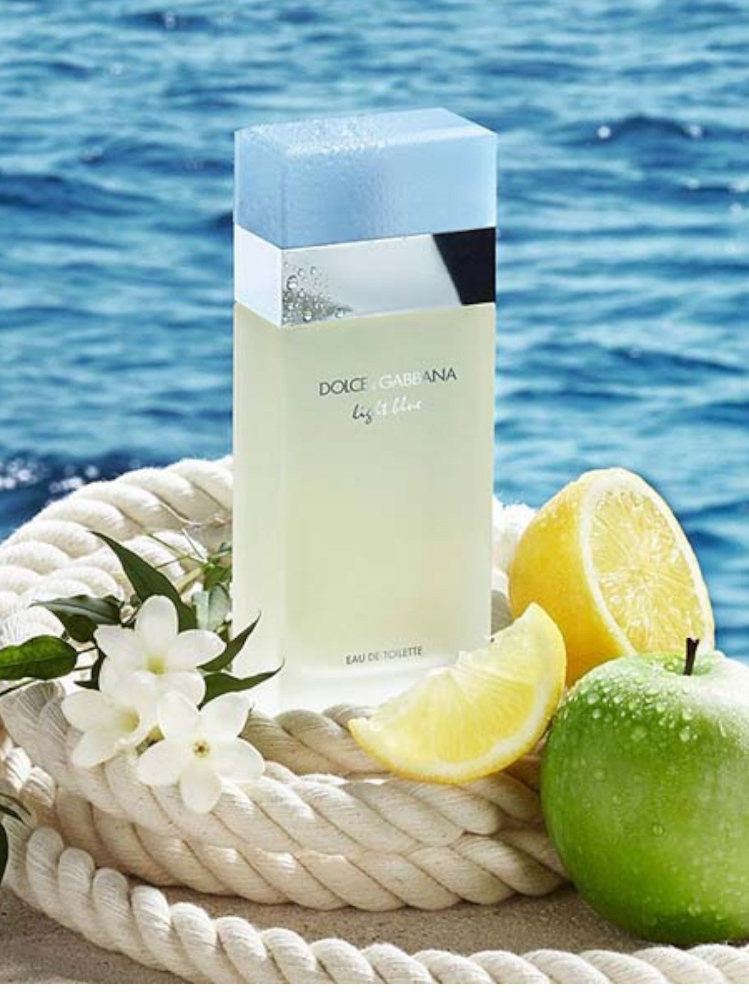 Dolce & Gabbana light blue perfume bottle with lemons and green apples on a rope by the sea. Dolce Gabbana Monza Outlet