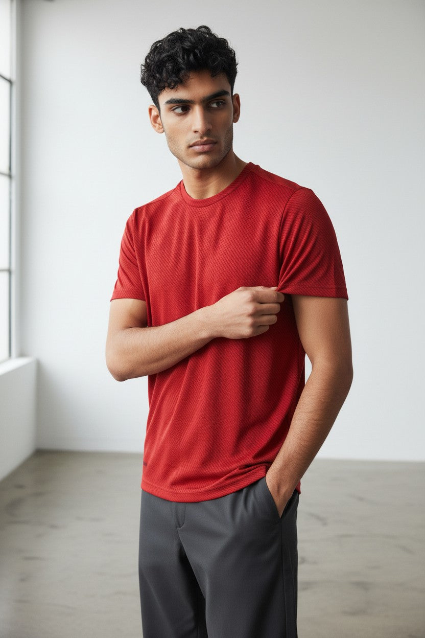 Man wearing a red shirt and gray pants standing in a minimalistic room. Adidas, Monza Outlet, Monza Fashion, Shein Outlet