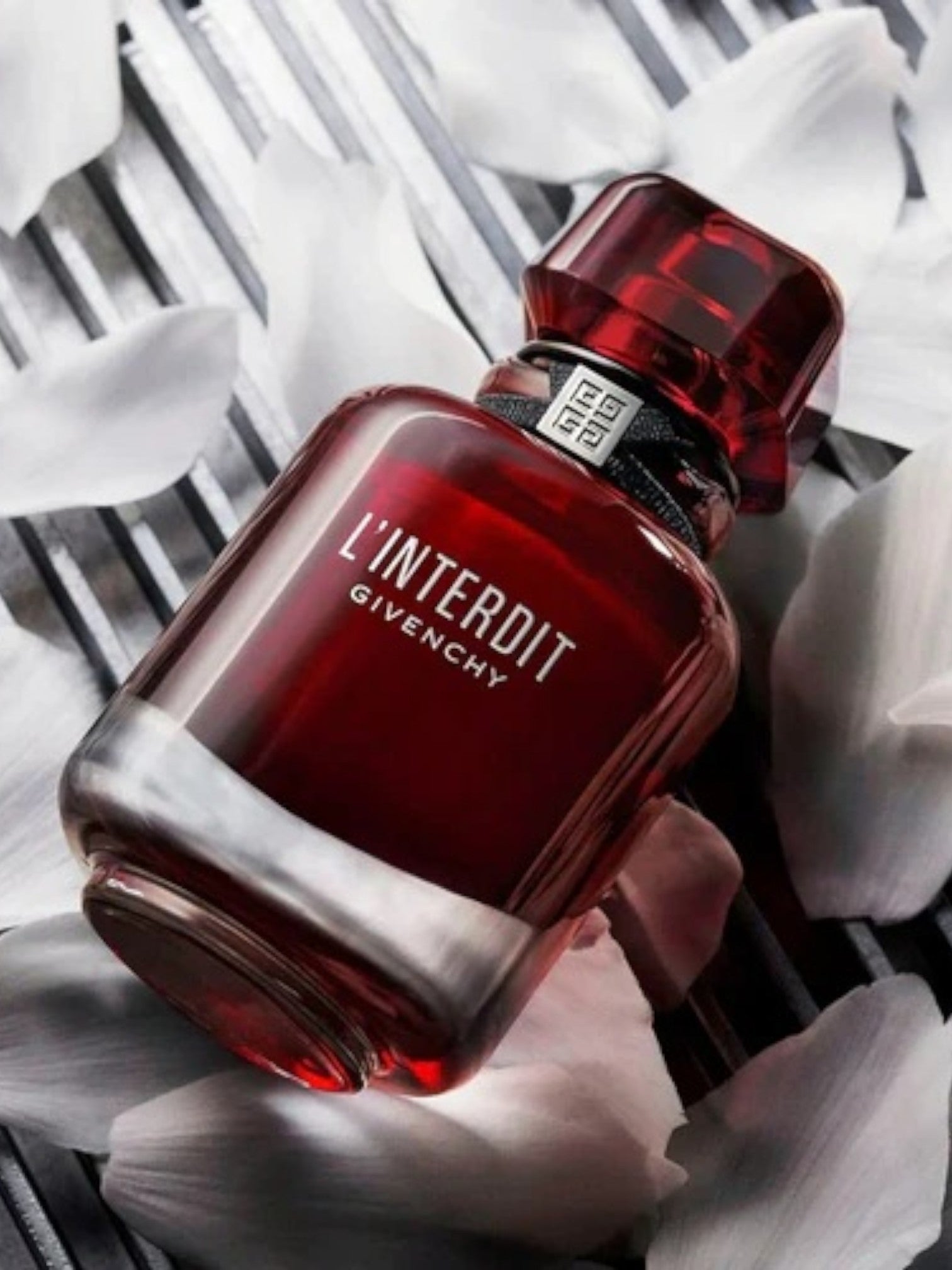 Red Givenchy perfume bottle on a white floral background monza outlet, Shein outlet, monza fashion