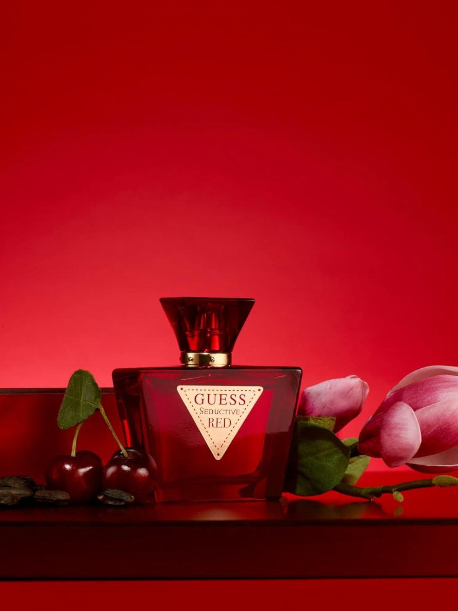 Red Guess perfume bottle with cherry and flower on a red background monza outlet, Shein outlet, monza fashion