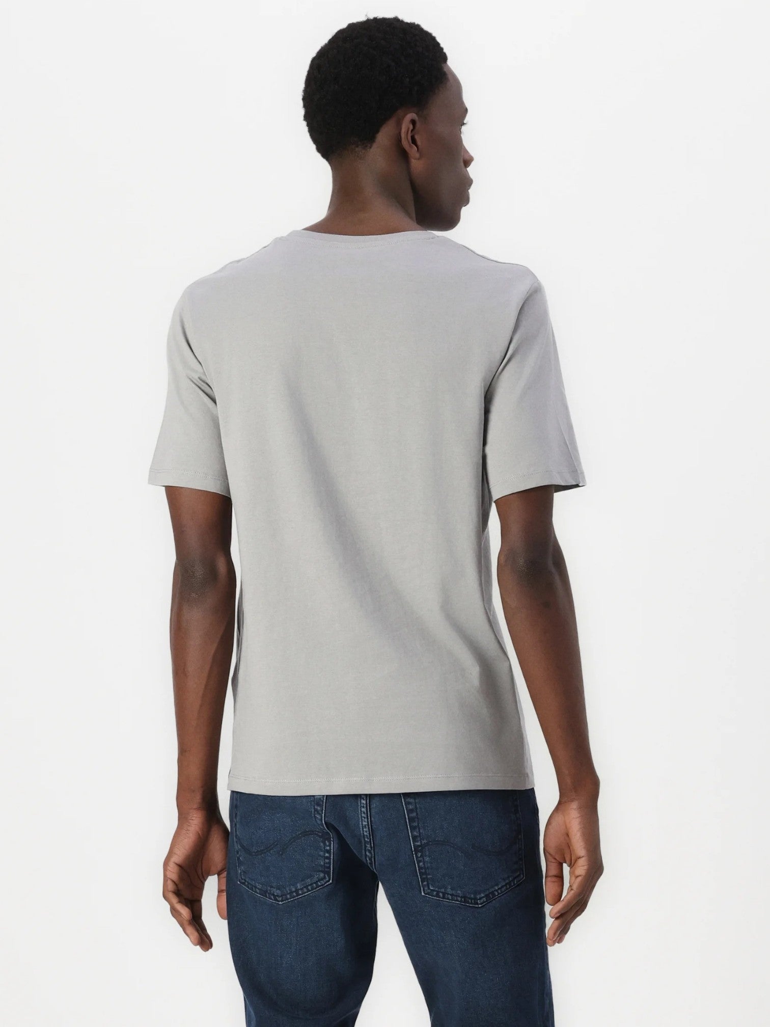 Man wearing a light gray t-shirt and blue jeans on a white background. Jack & Jones, Monza Outlet, Monza Fashion, Shein Outlet 