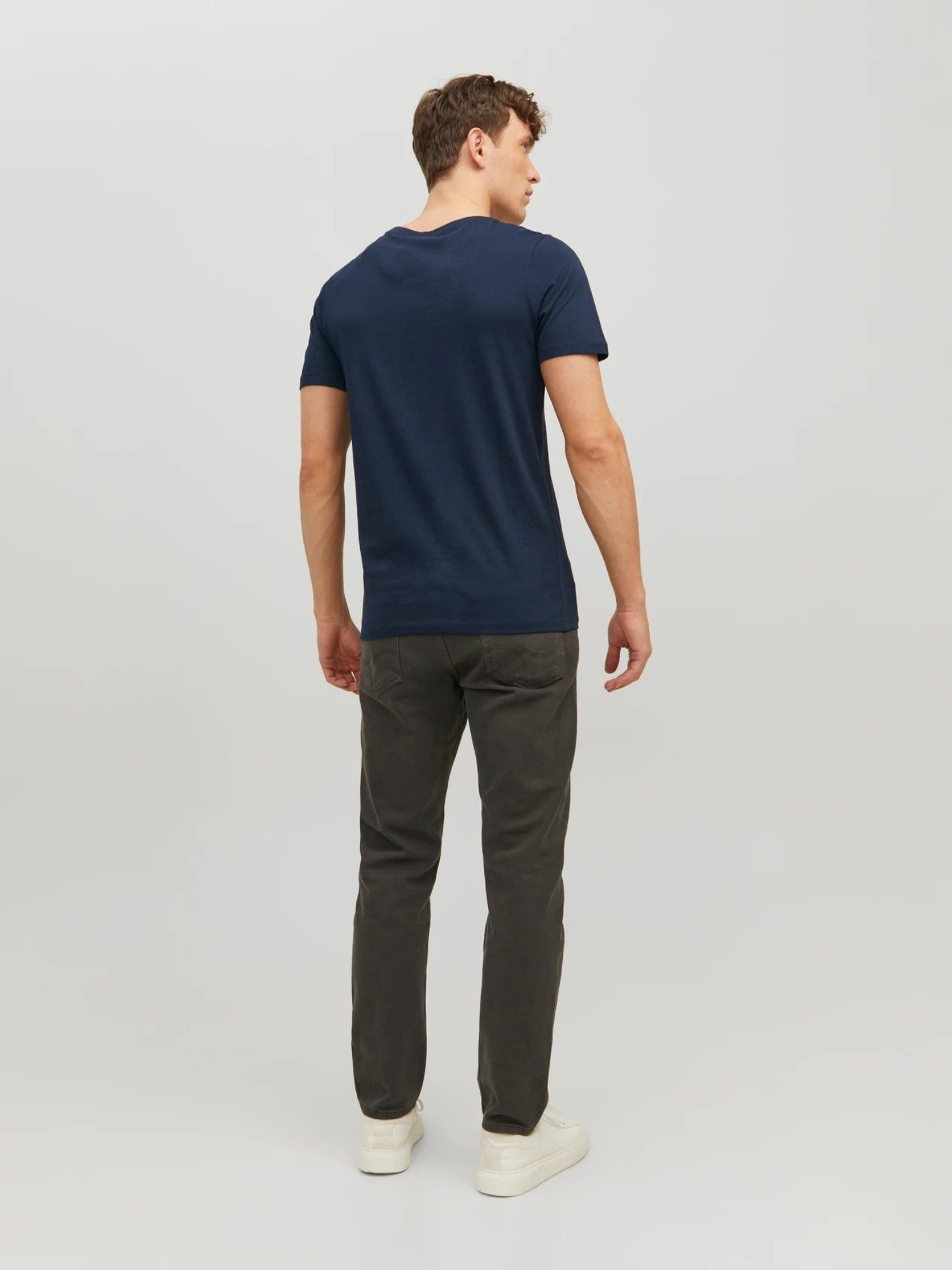 Man wearing a navy t-shirt and dark pants on a light gray background. Jack & Jones, Monza Outlet, Monza Fashion, Shein Outlet 