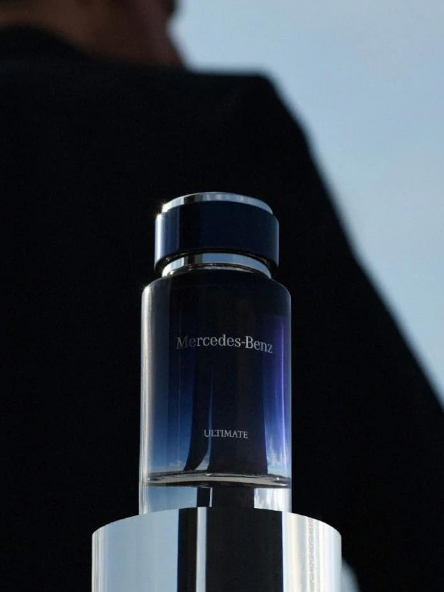 Mercedes-Benz Ultimate perfume bottle on a reflective surface with a blurred background. Mercedes Benz, Monza Outlet, Monza Fashion, Shein Outlet