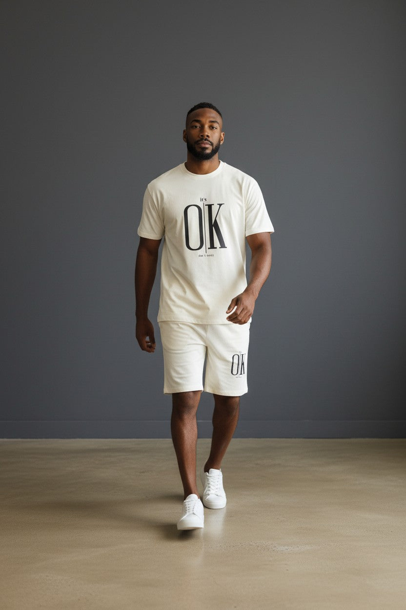 Man wearing a white t-shirt and shorts with OK branding against a gray background. Antler, Monza Outlet, Monza Fashion, Shein Outlet
